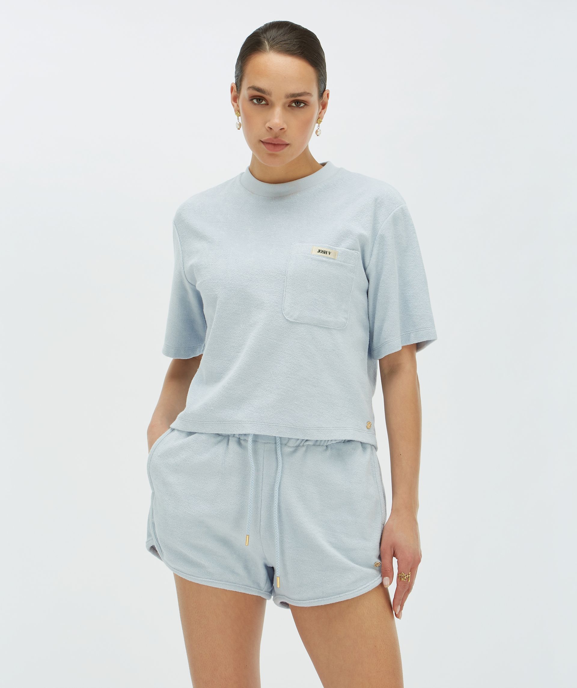 Model draagt een oversized T-shirt in de kleur lichtblauw met een borstzak voorzien van het JOSH V-logo - Josh V.