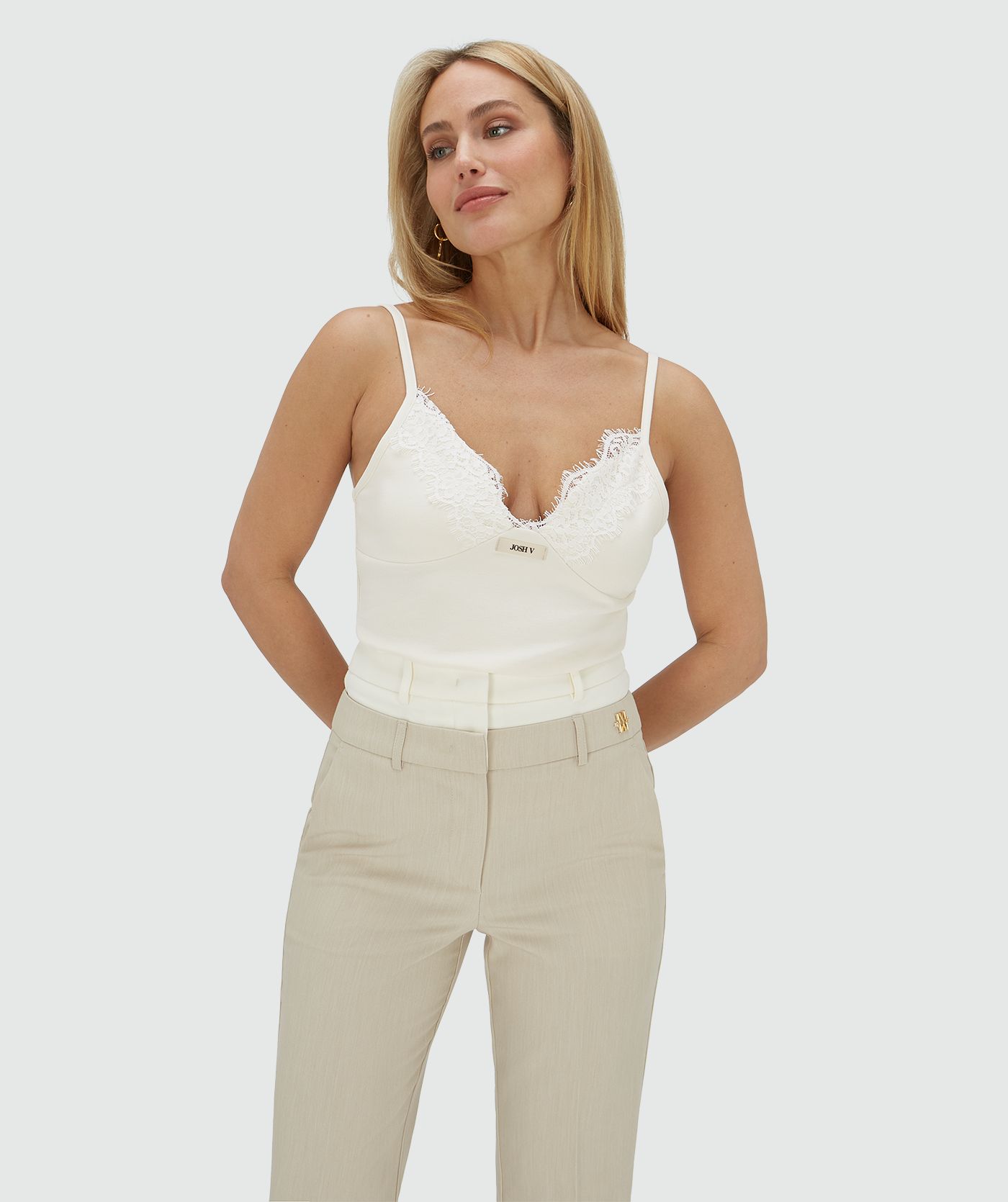 Model draagt een slim fit top in de kleur Creme White met kanten afwerkingen