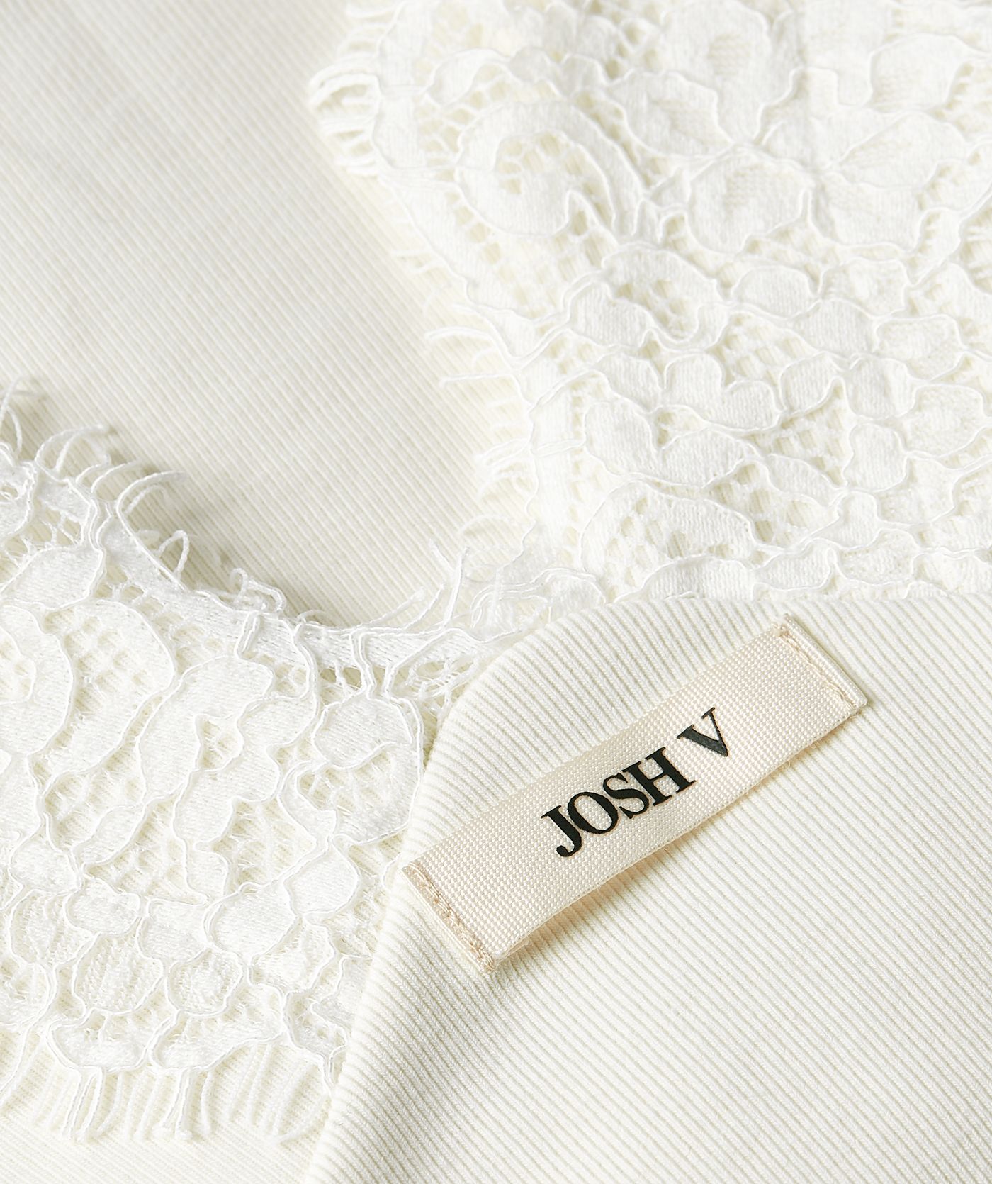 Close-up van een slim fit top in de kleur Creme White met kanten afwerkingen met een klein JOSH V-label voorop