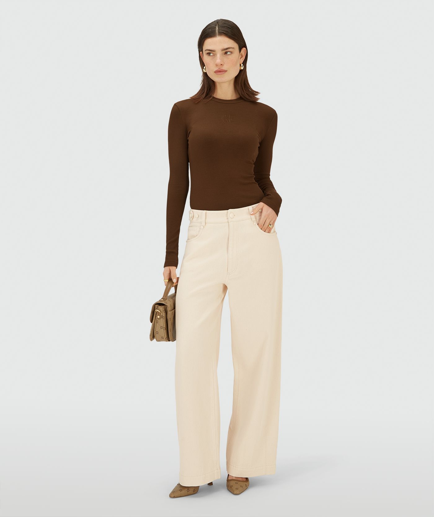 Model draagt een Ecru high-waist, wide-leg broek met steekzakken