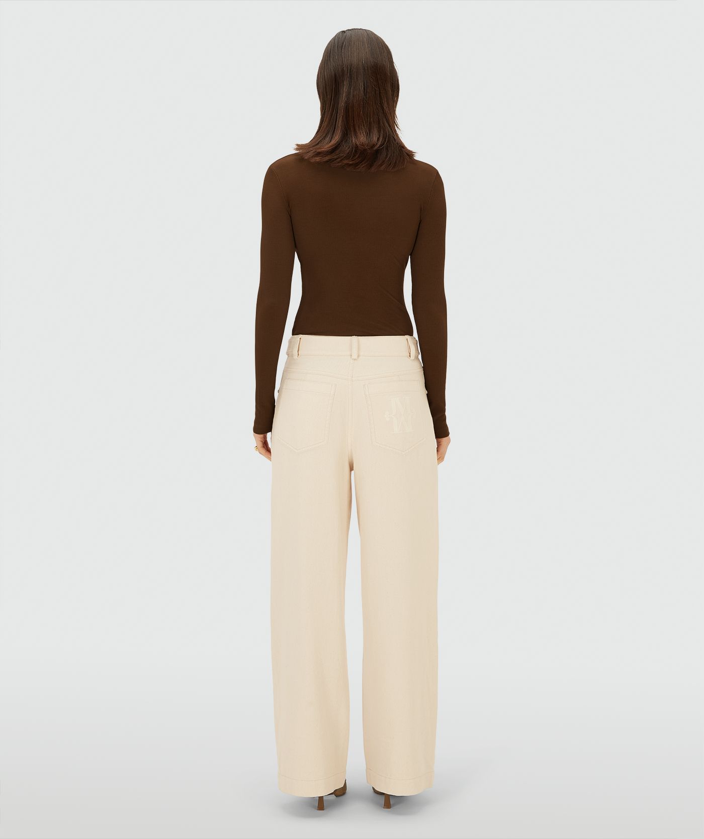 Achteraanzicht van een model in een Ecru high-waist, wide-leg broek met steekzakken en JV-monogram op de achterkant