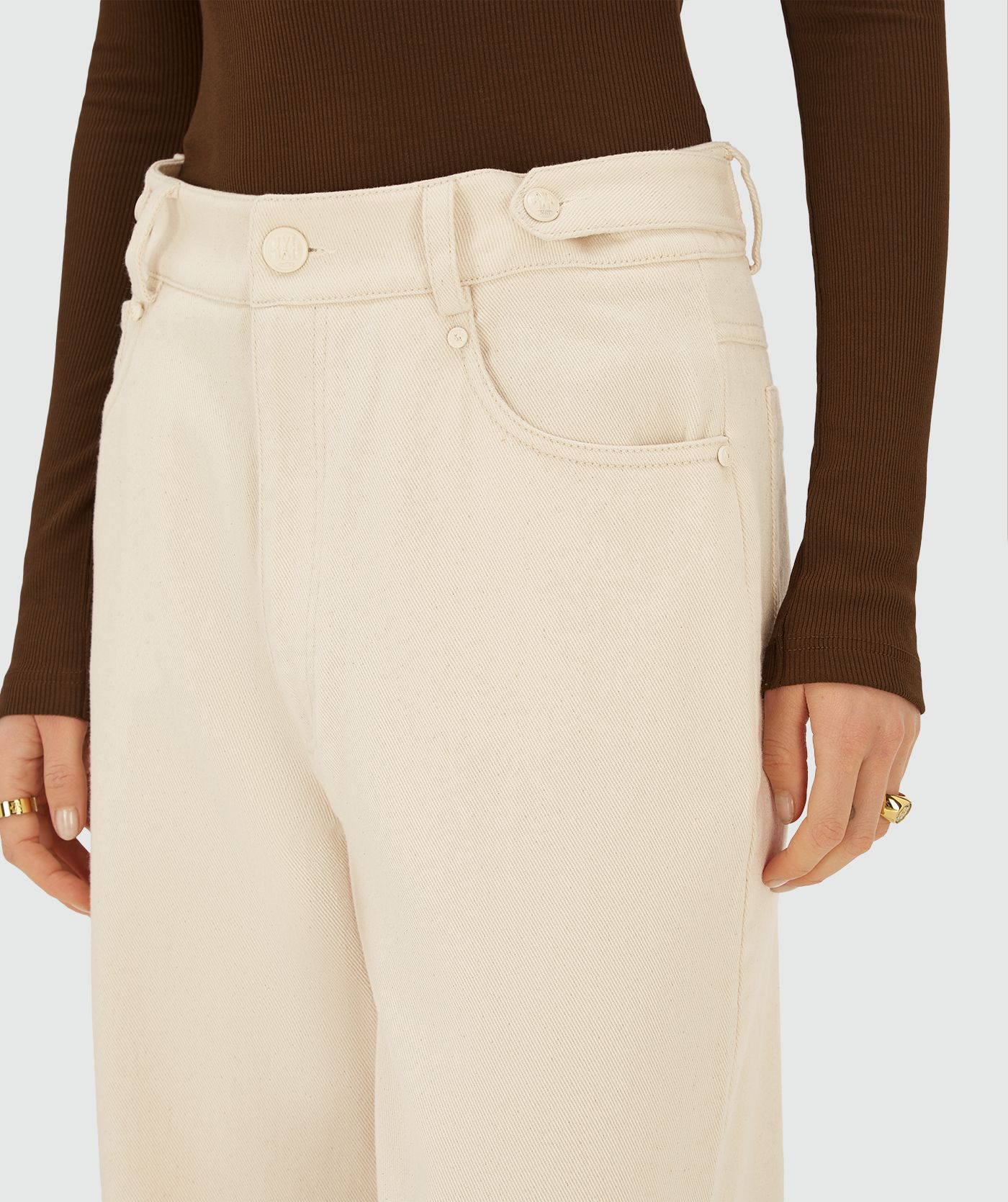 Model draagt een Ecru high-waist, wide-leg broek met steekzakken