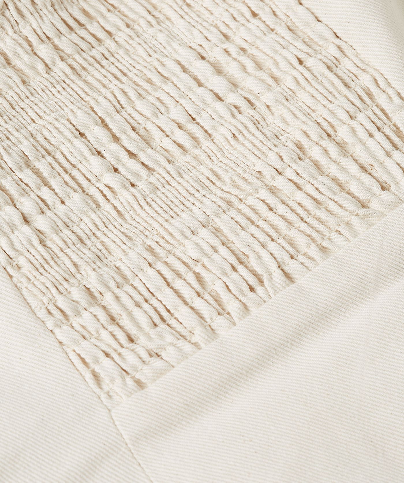 Close-up van het elastiek aan de achterkant van de gebroken witte bustier top dat zorgt voor een beter zit comfort.