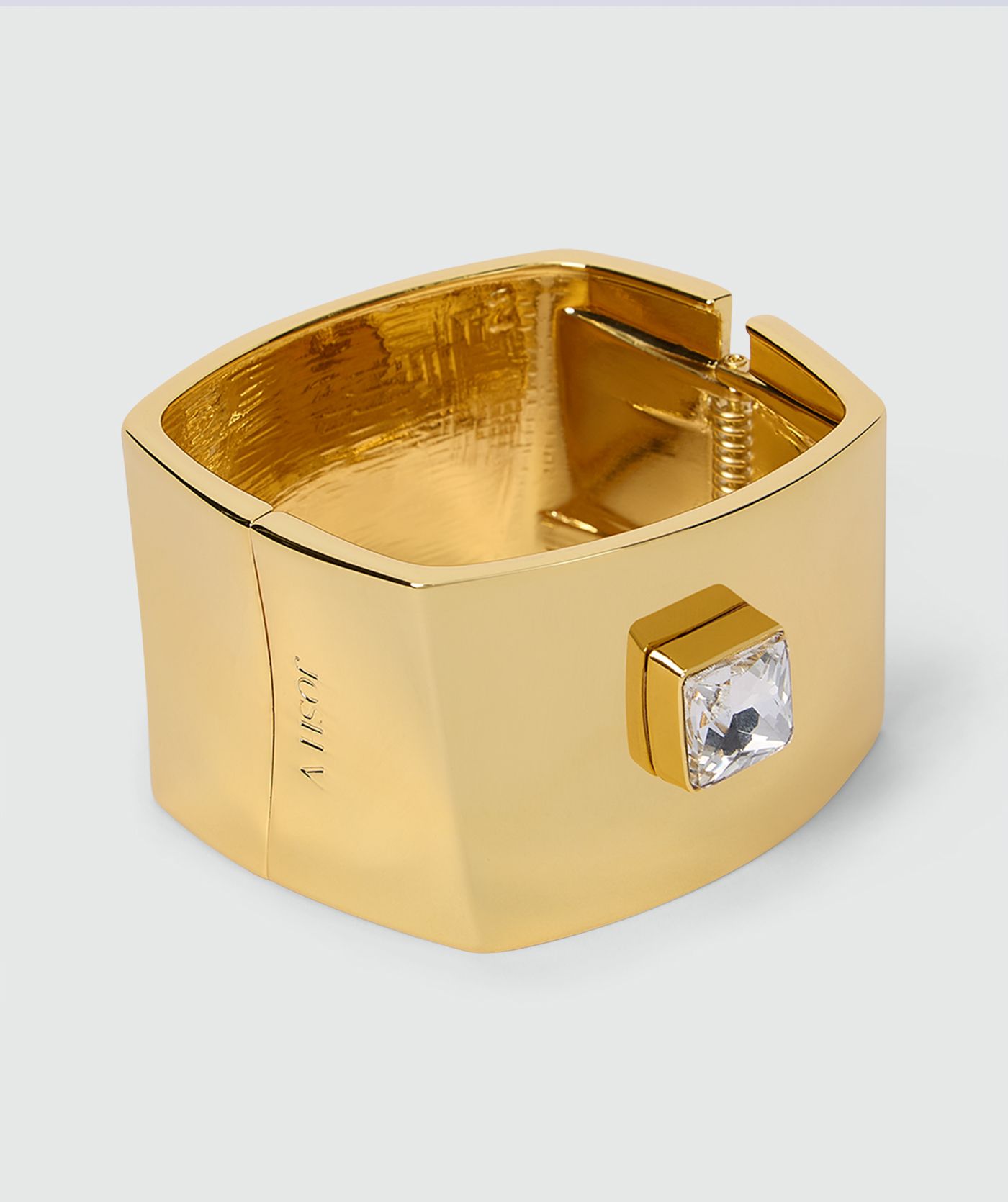 Goudkleurige armband met brede band, vierkante transparante steen en veersluiting, afgewerkt met een subtiel JOSH V-logo aan de zijkant zonder model, weergegeven op een lichtgrijze achtergrond