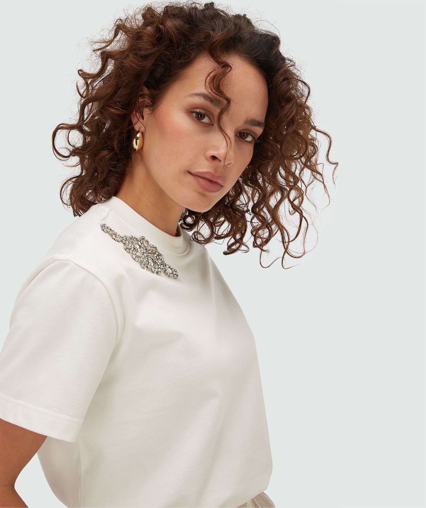Zijaanzicht van model in een oversized T-shirt met strass in de kleur Off White