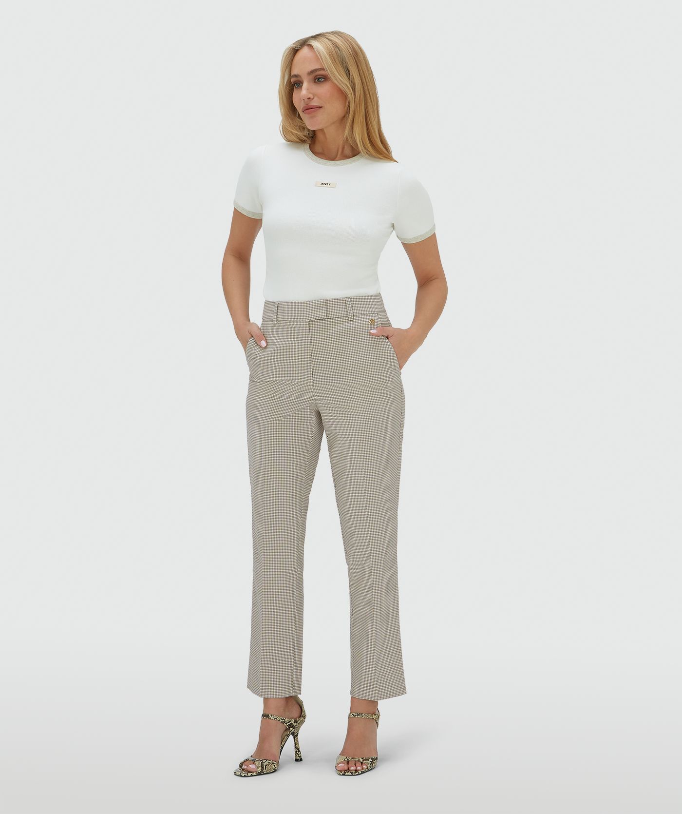 Het model draagt een mid rise pantalon in het Stone Check-patroon
