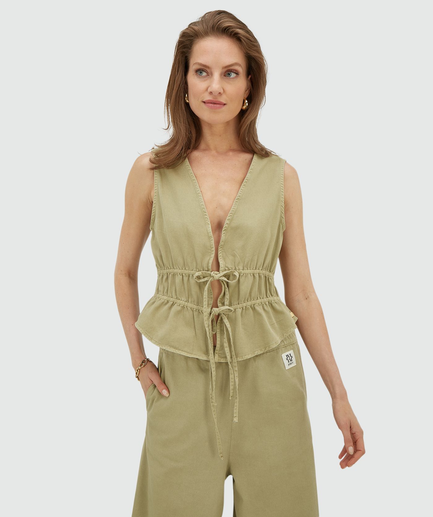 Model draagt een getailleerde top met peplum in de kleur Dark Pistachio