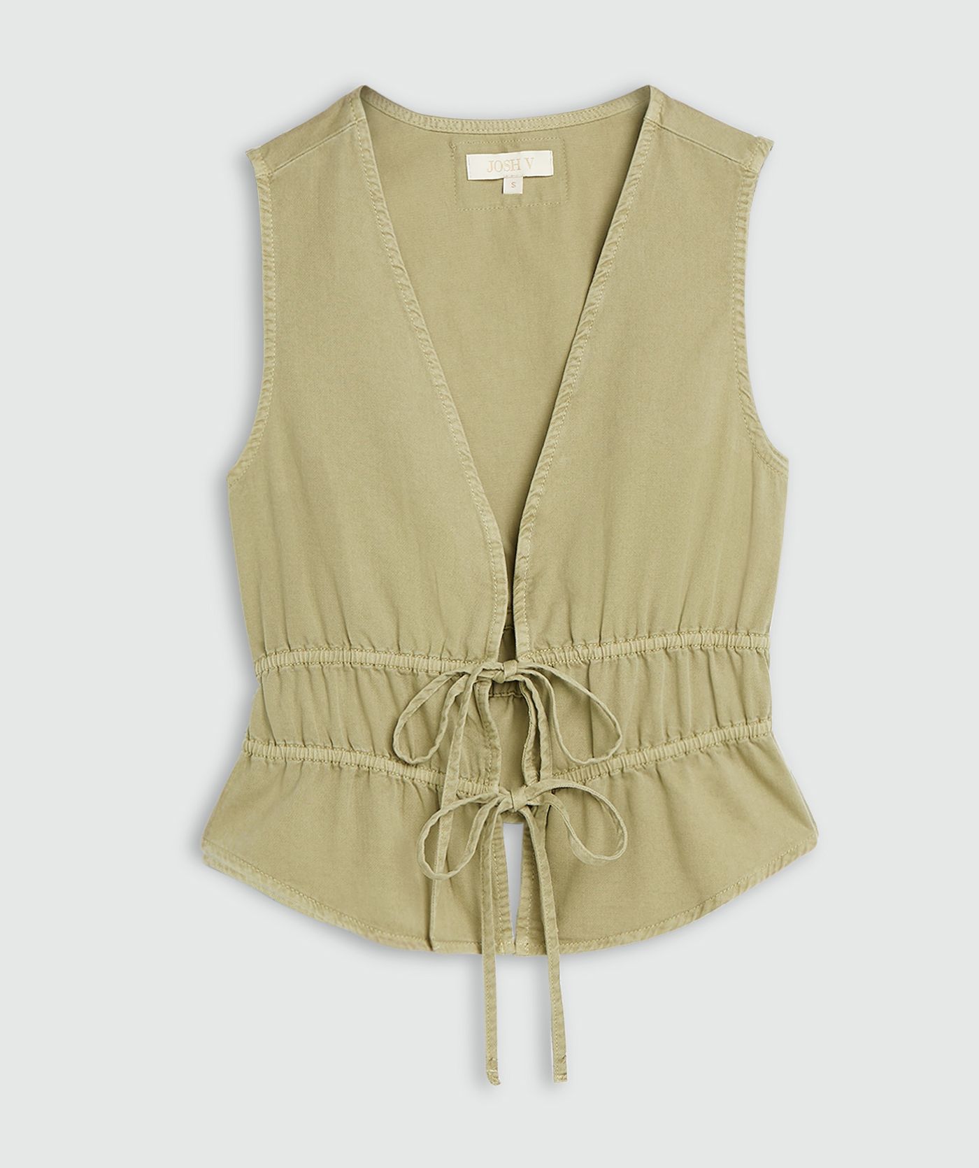 Een getailleerde top met peplum in de kleur Dark Pistachio, weergegeven op een lichtgrijze achtergrond