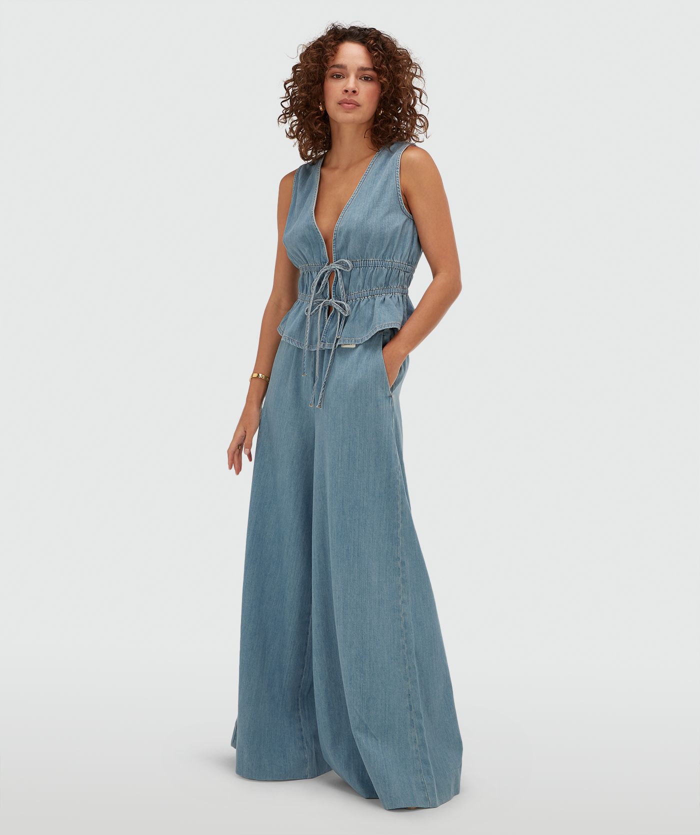 Model draagt een getailleerde top met peplum in de kleur Mid Blue Denim