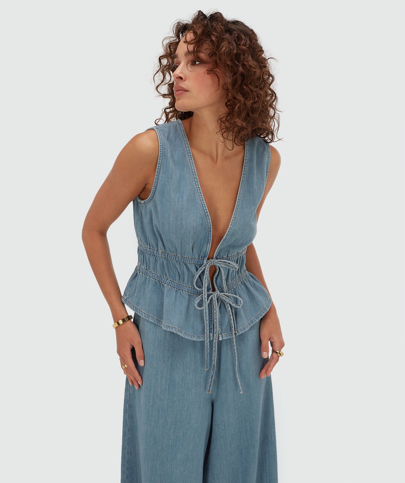 Model draagt een getailleerde top met peplum in de kleur Mid Blue Denim