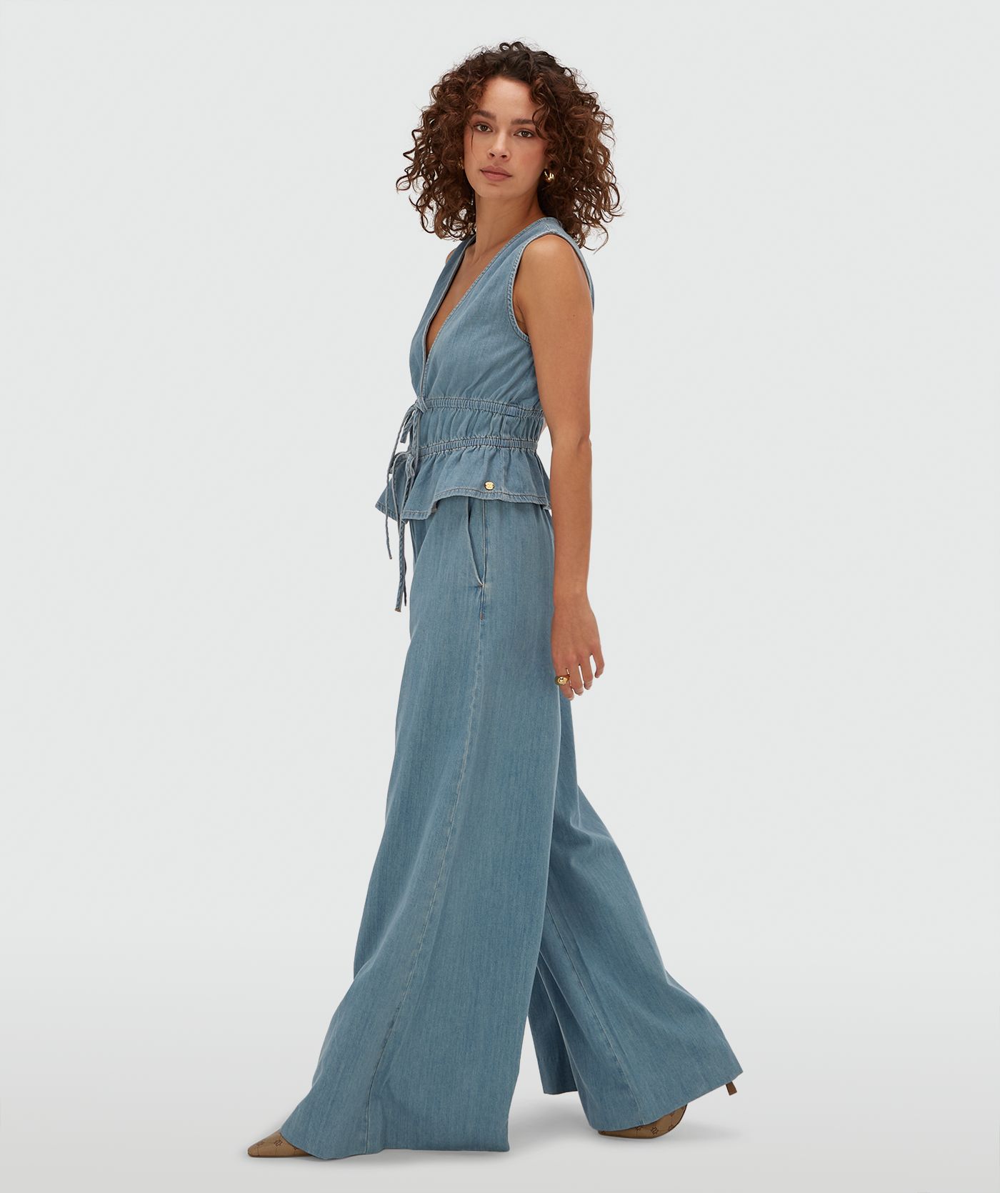 Zijaanzicht van een model in een getailleerde top met peplum in de kleur Mid Blue Denim