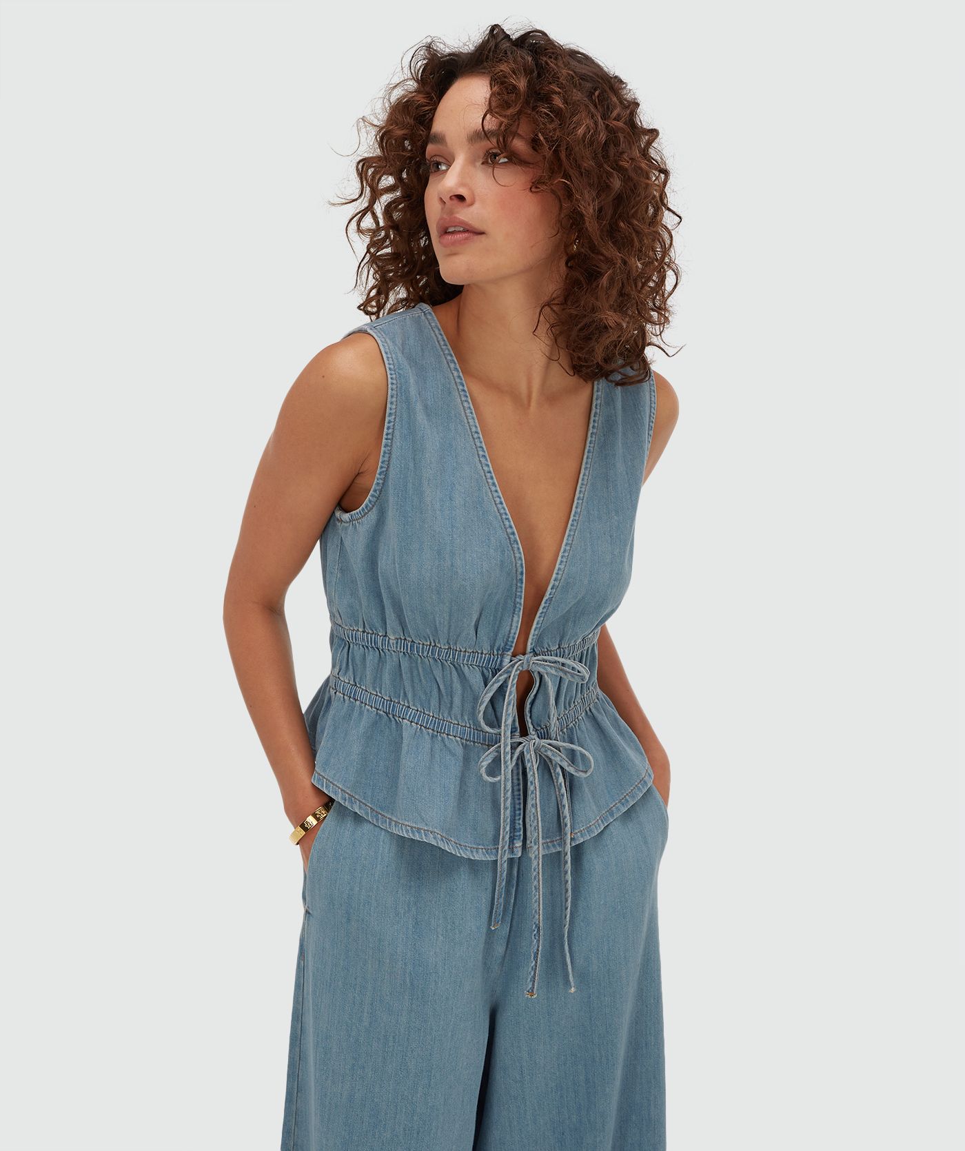Model draagt een getailleerde top met peplum in de kleur Mid Blue Denim