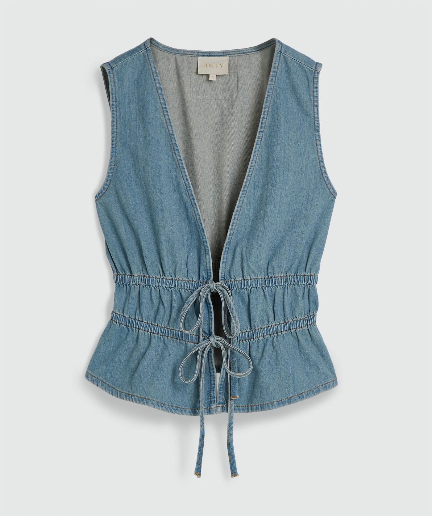 Een getailleerde top met peplum in de kleur Mid Blue Denim, zonder model, weergegeven op een lichtgrijze achtergrond