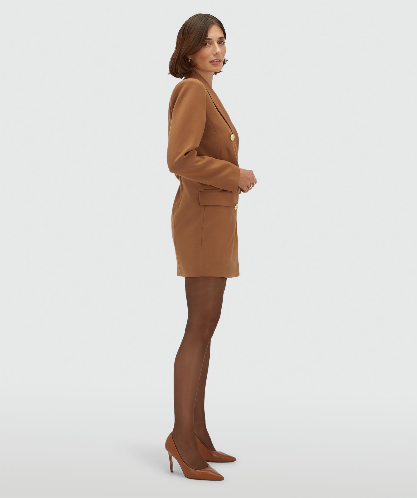 Zijaanzicht van een model in een cognac kleurige fitted bladerjurk