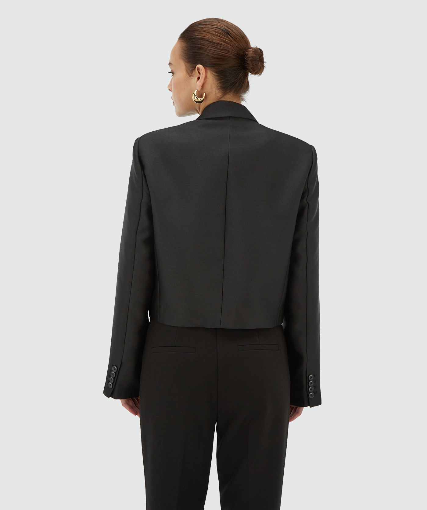 Achteraanzicht van een model in een zwarte korte blazer met strik aan de voorzijde - JOSH V