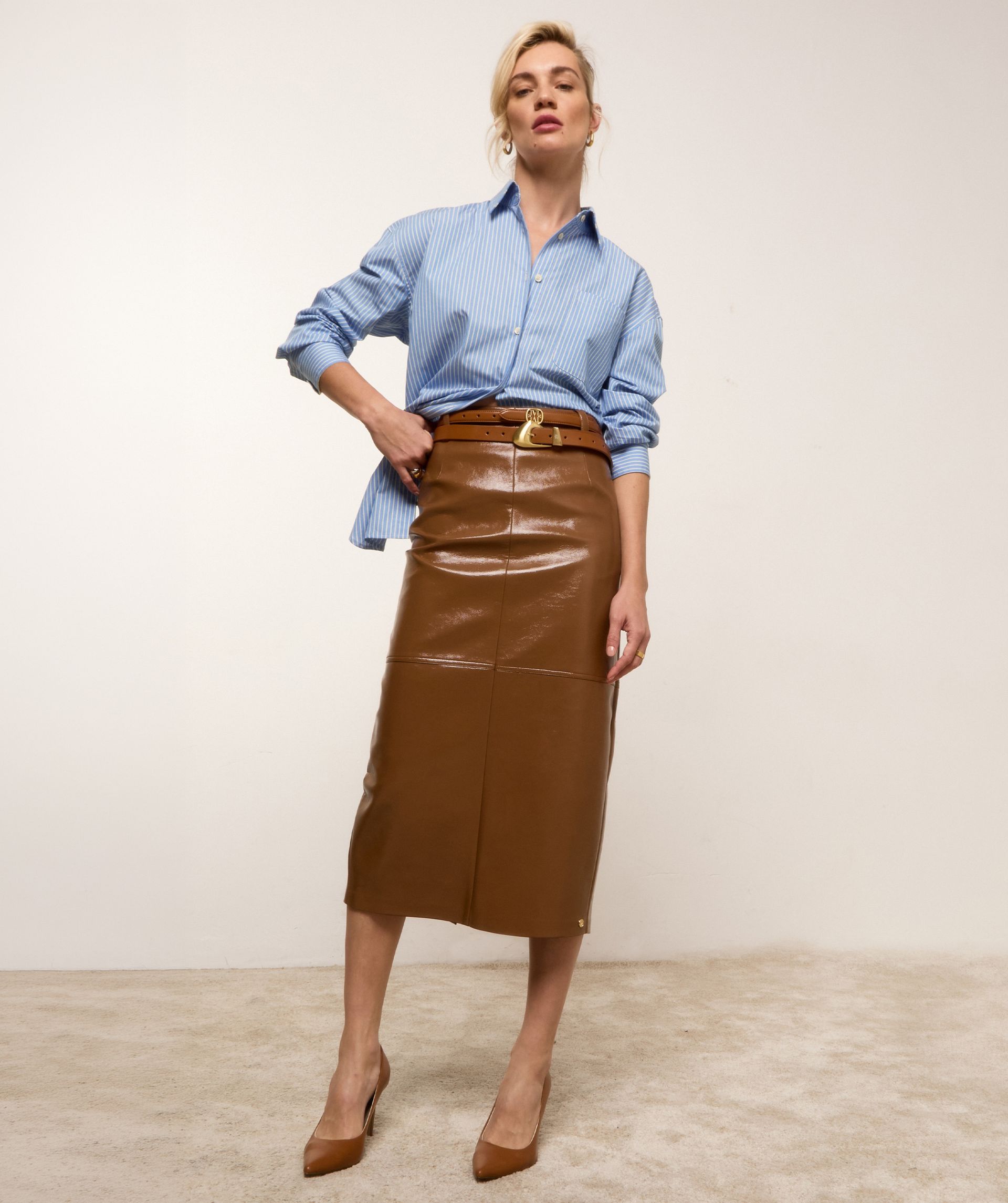 Model draagt de lichtblauw wit gestreepte blouse op een lange lak look rok.