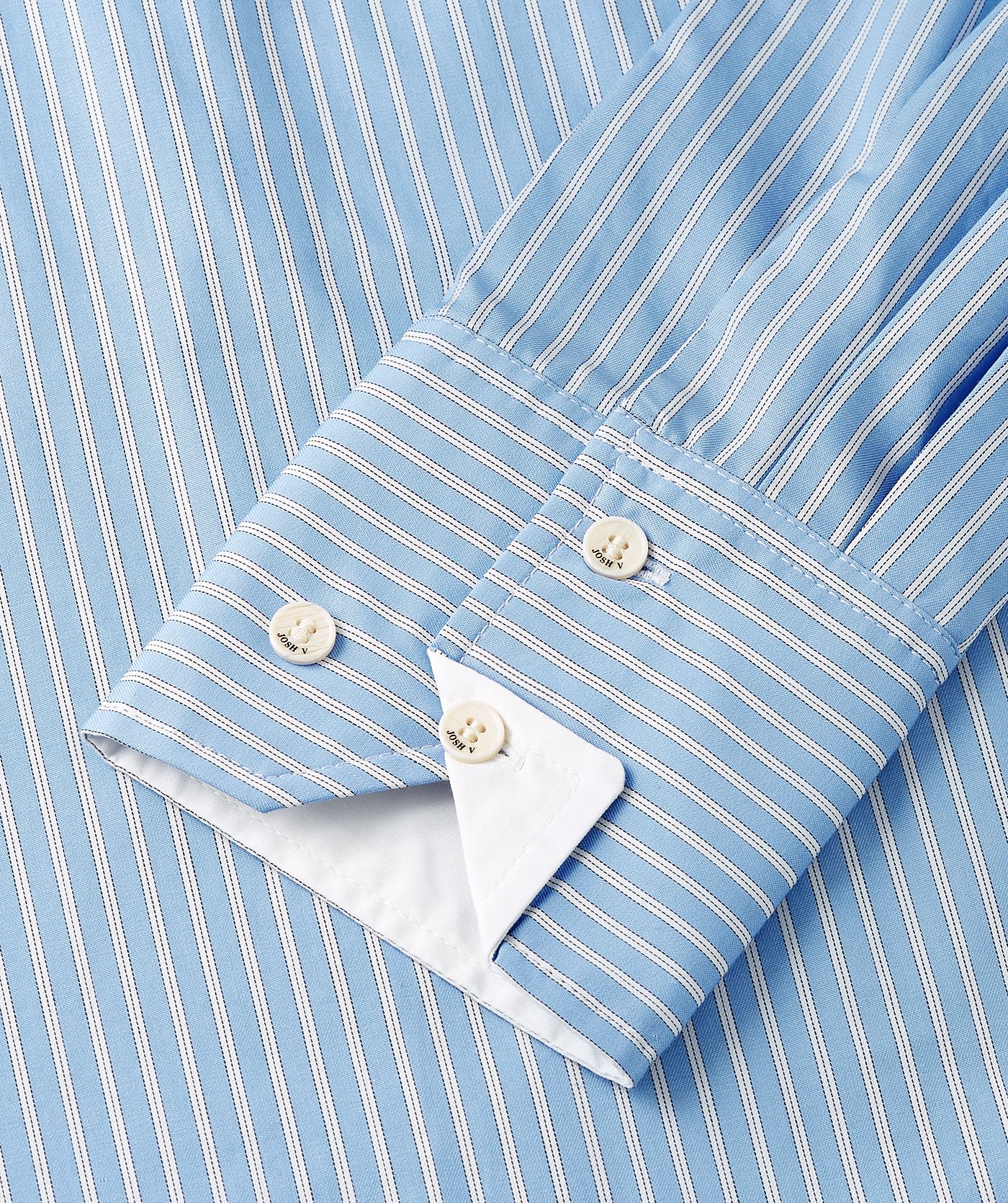 Close-up van de manchetknopen van de lichtblauw met wit gestreepte blouse.