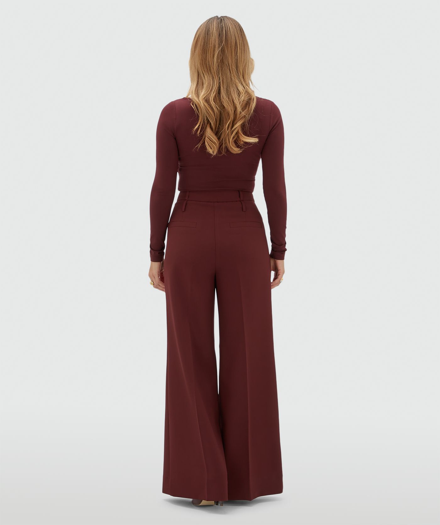 Achteraanzicht van een model in een donkerrode pantalon.