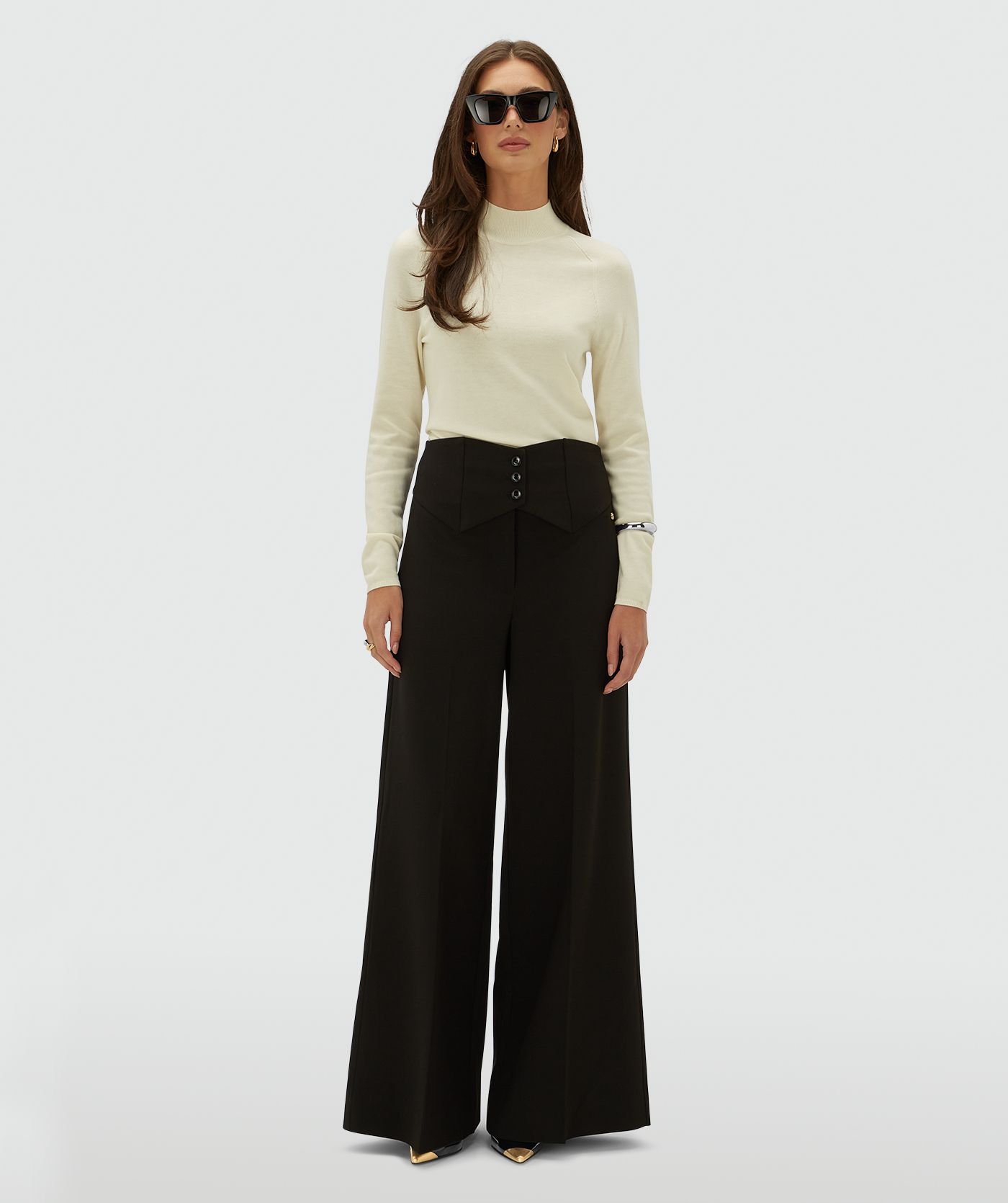 Model draagt een creme kleurige coltrui, op een lichtgrijze achtergrond