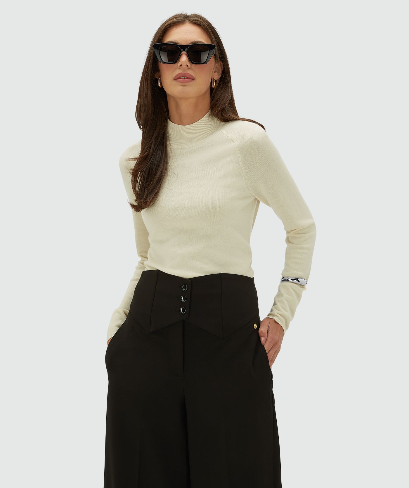 Model draagt een creme kleurige coltrui, op een lichtgrijze achtergrond