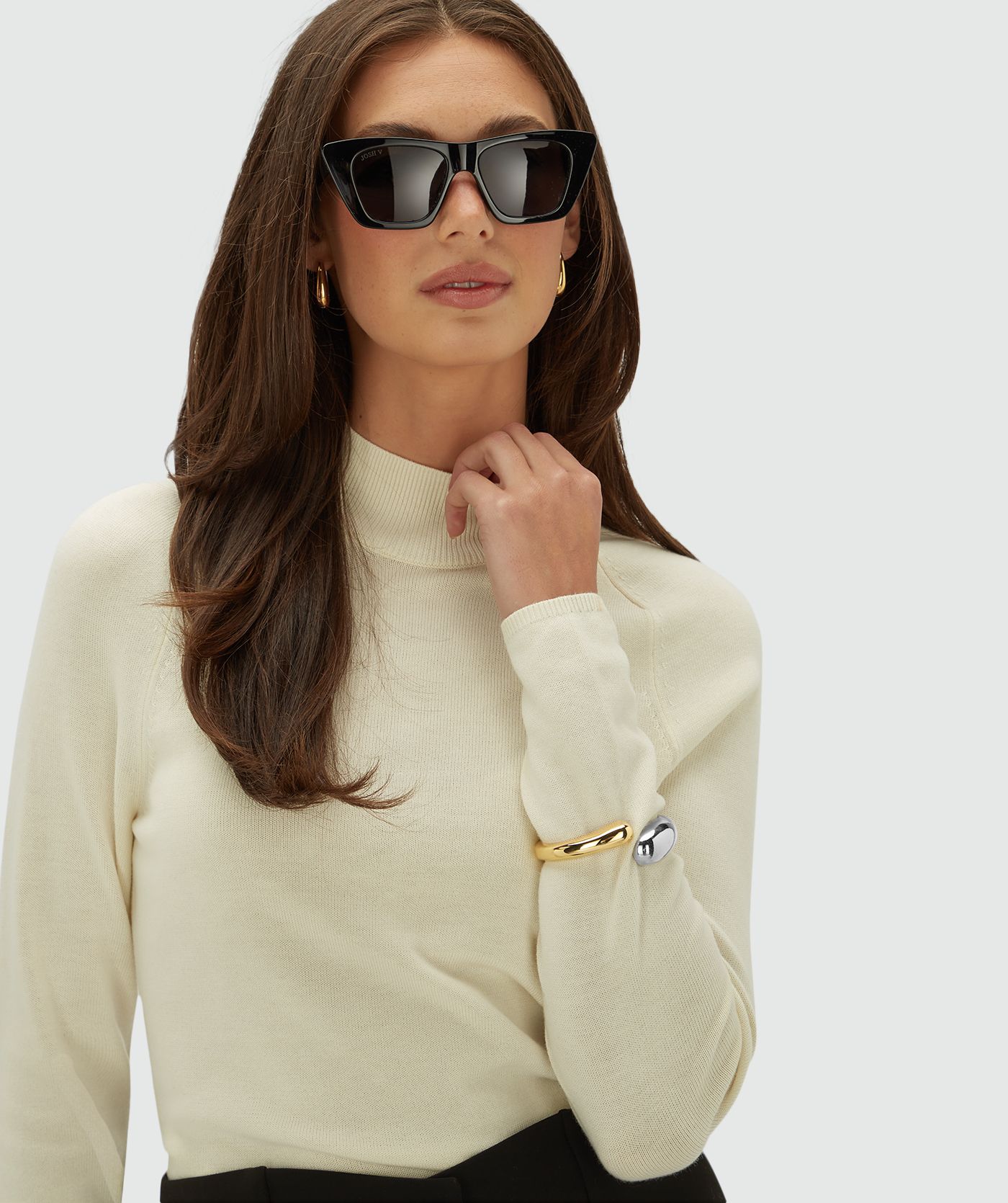 Model draagt een creme kleurige coltrui, op een lichtgrijze achtergrond