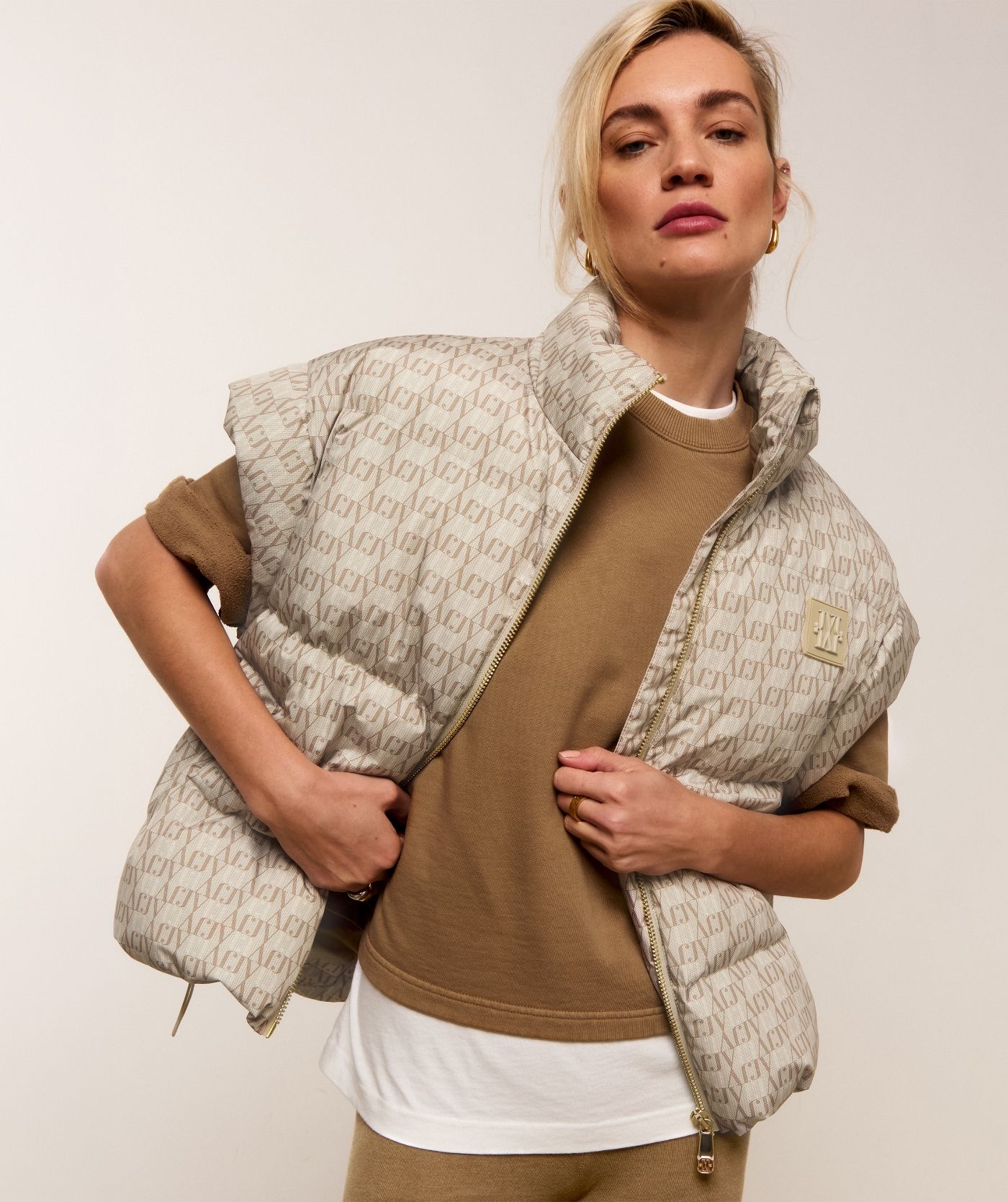 Model draagt een bodywarmer met een overall JOSH V-logo print in de kleur beige.