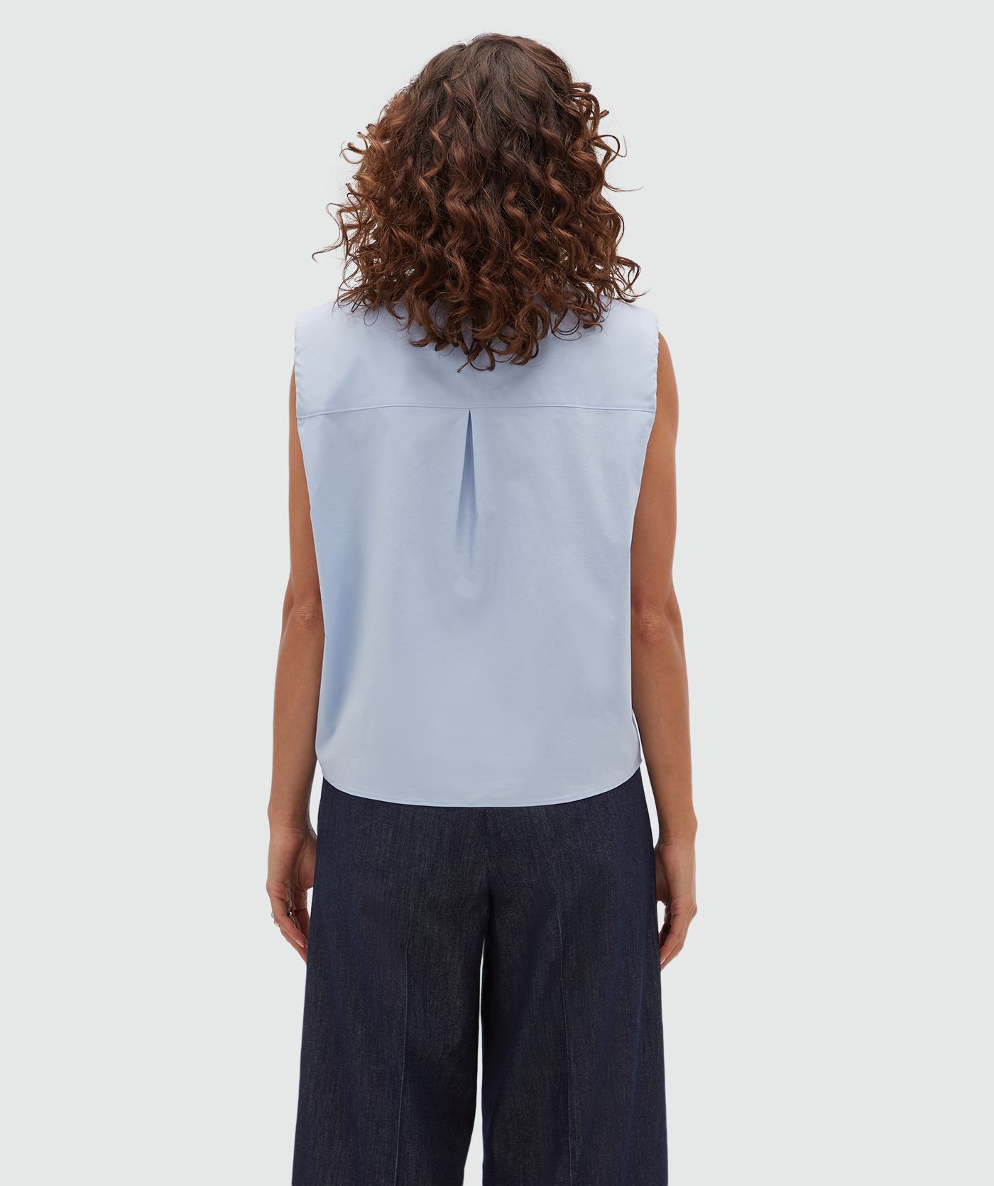 Achteraanzicht van een model in een lichtblauwe blouse.
