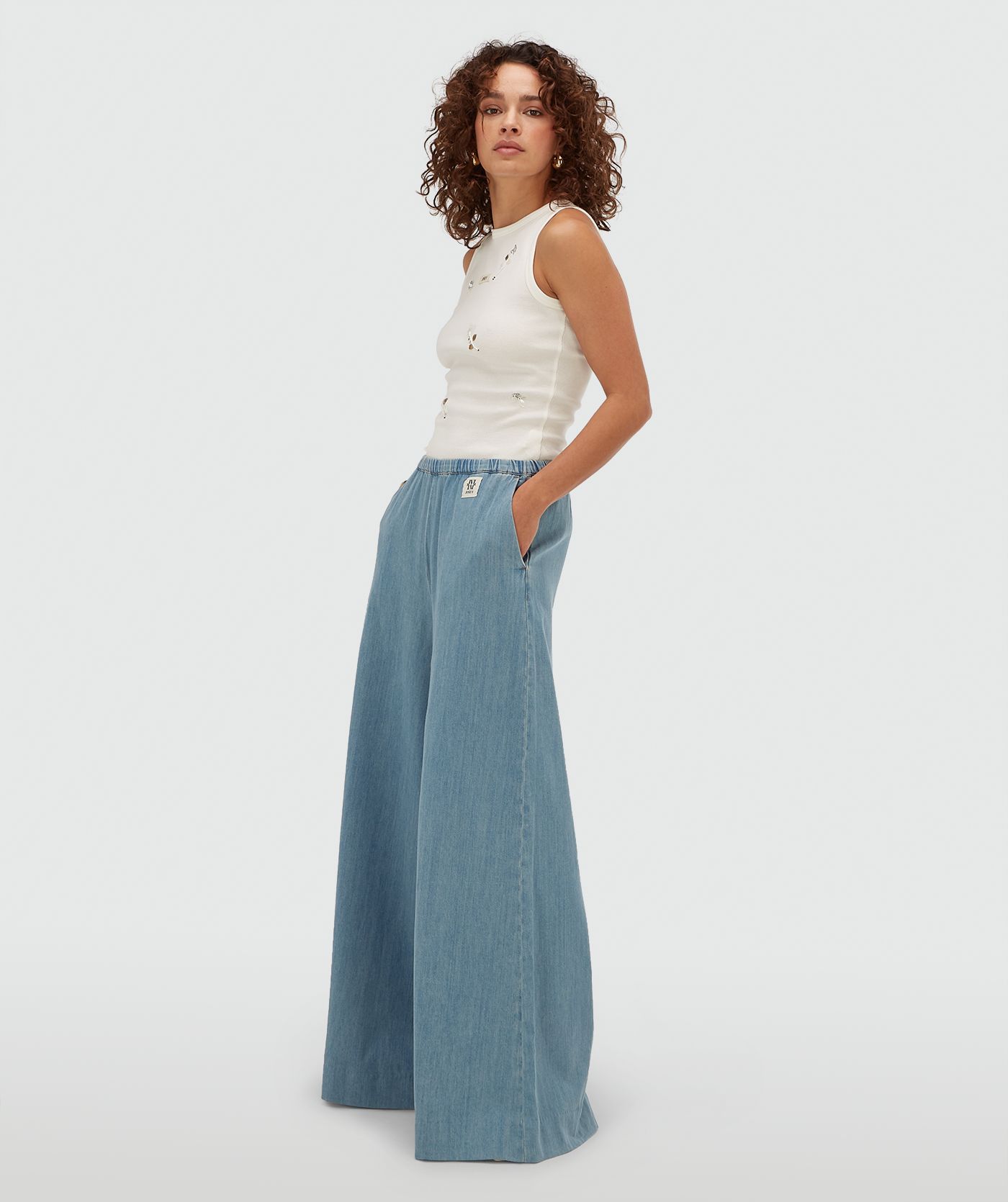 Model draagt een slim fit top met kralen details in de kleur Off White