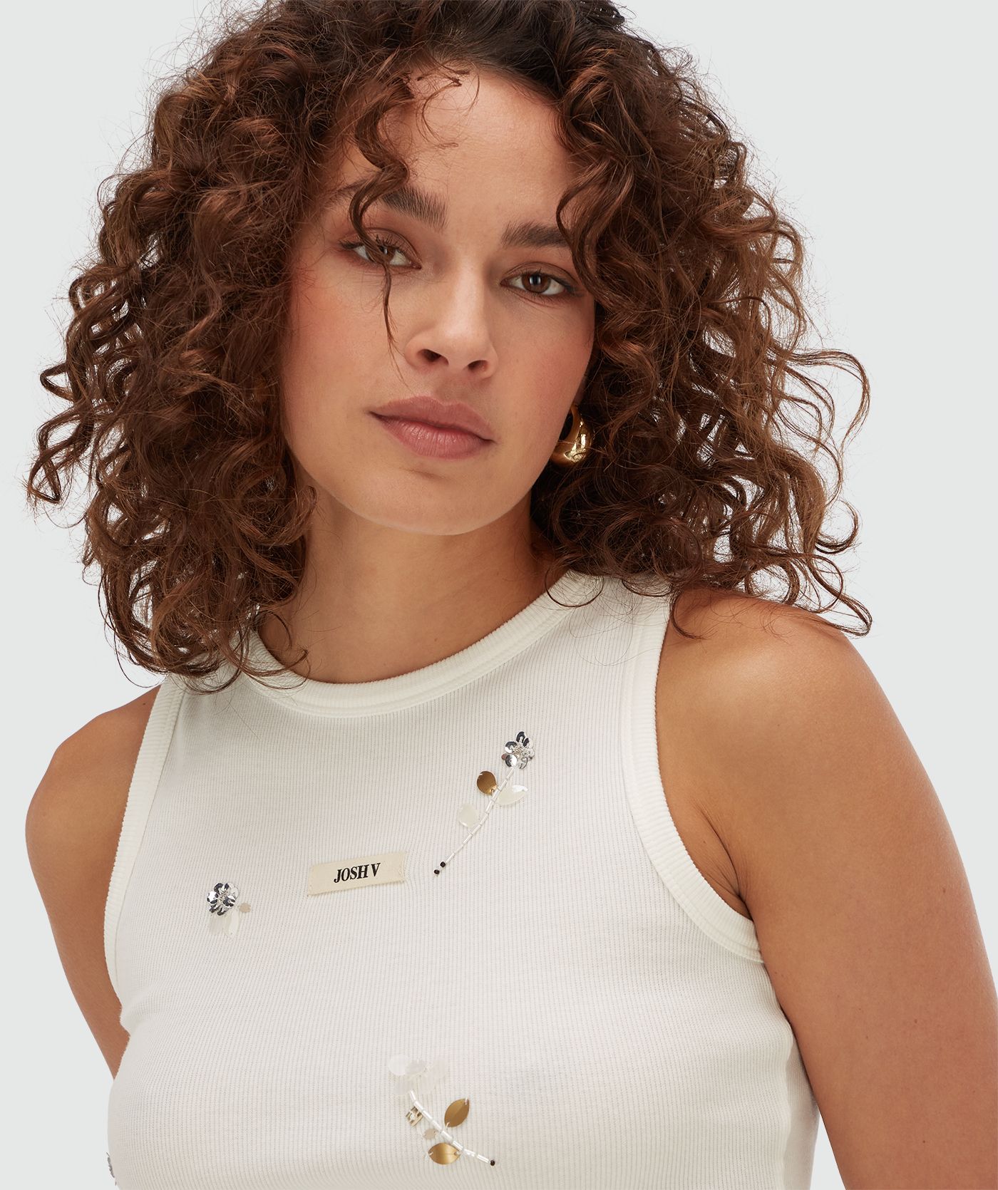 Model draagt een slim fit top met kralen details in de kleur Off White