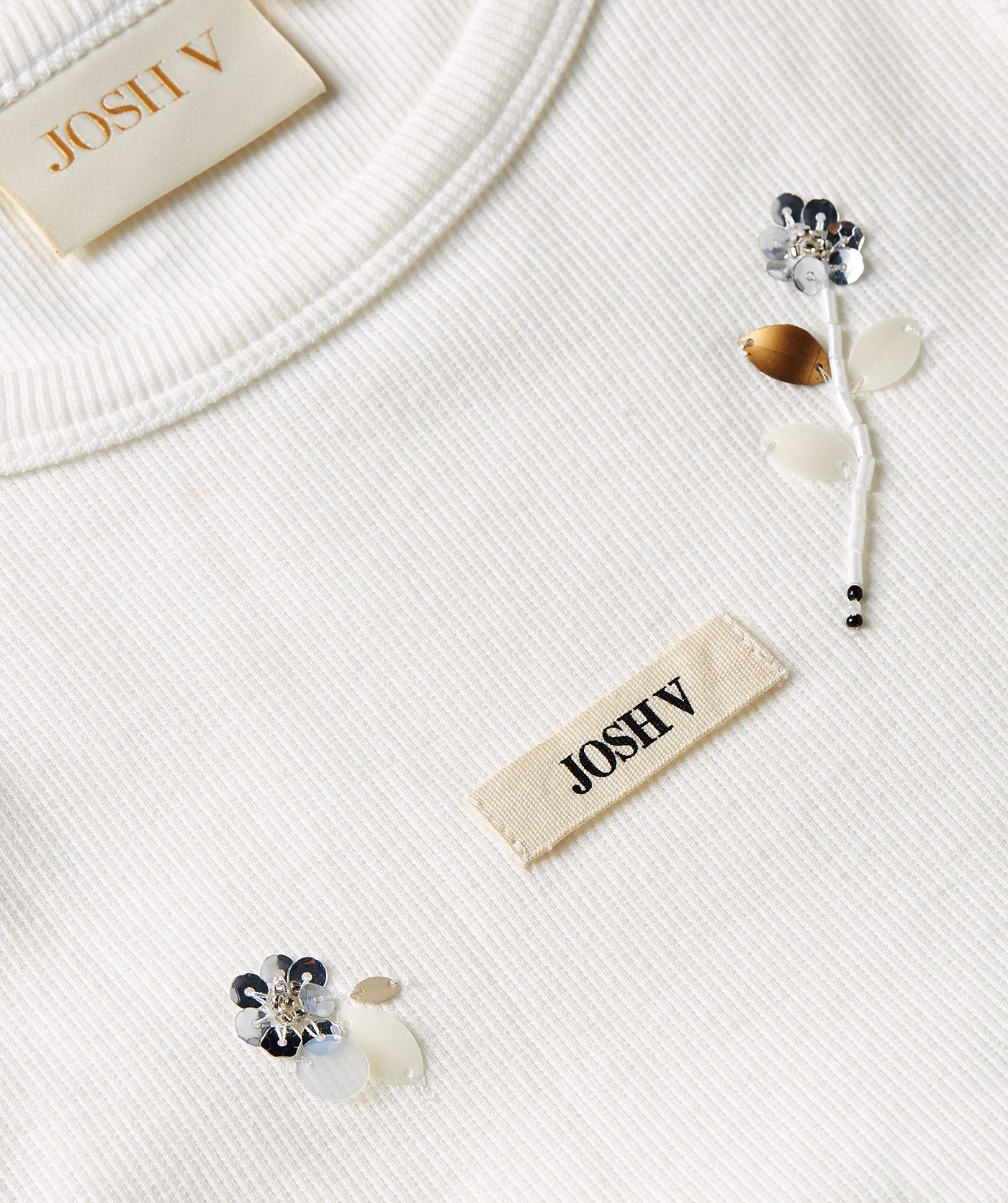 Close-up van een slim fit top met kralen details in de kleur Off White
