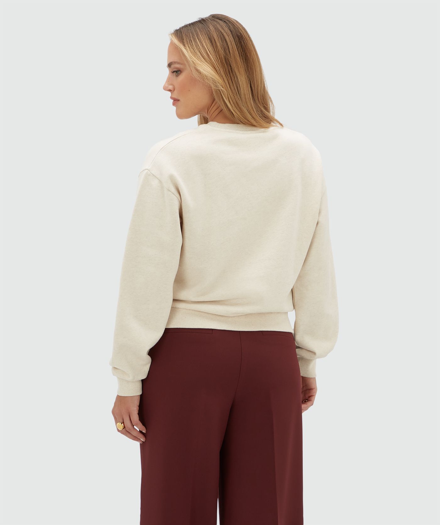Achteraanzicht van een model in een beige sweater.