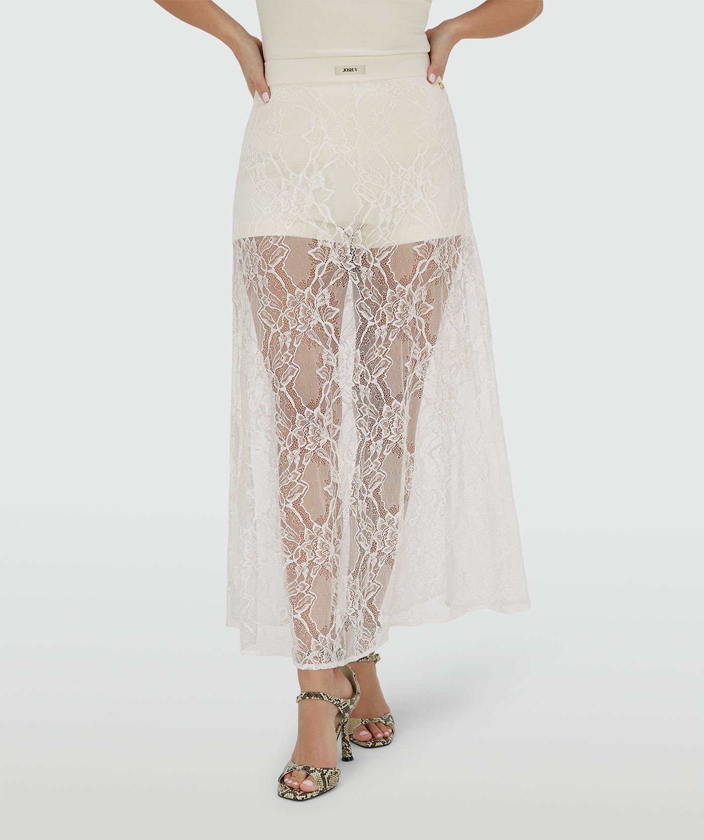 Ingezoomd beeld een high waisted kanten rok in de kleur Crème Wit, met een jersey broekje eronder. In het midden van de elastische tailleband is het JOSH V-label zichtbaar