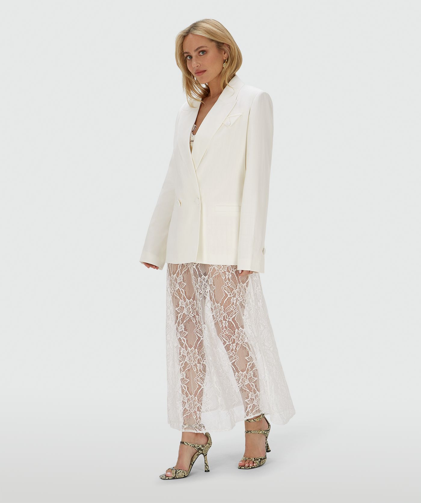 Model draagt een high waisted kanten rok in de kleur Crème Wit, met een jersey broekje eronder. In het midden van de elastische tailleband is het JOSH V-label zichtbaar