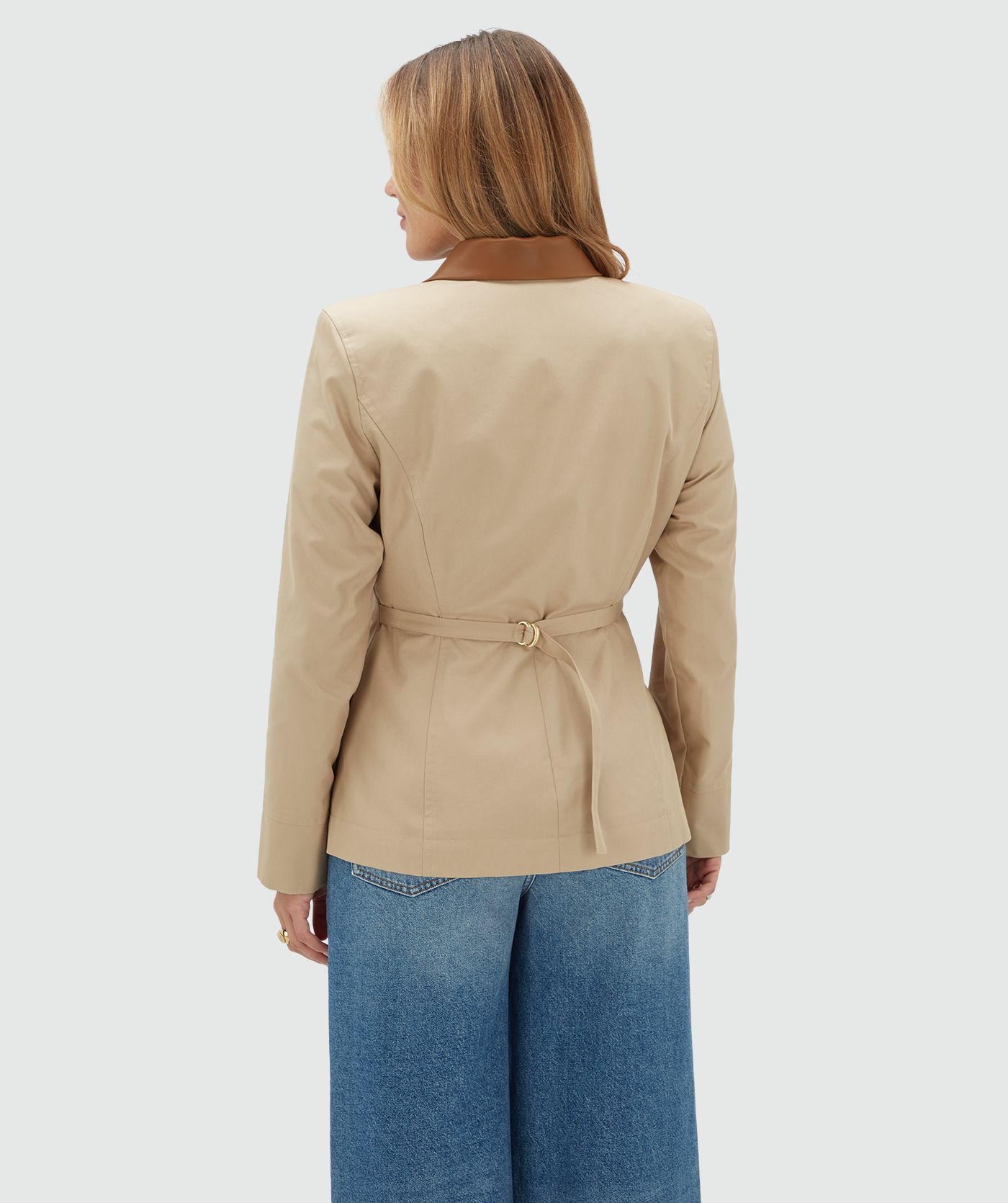 Achteraanzicht van een model in een beige jasje met leren details.