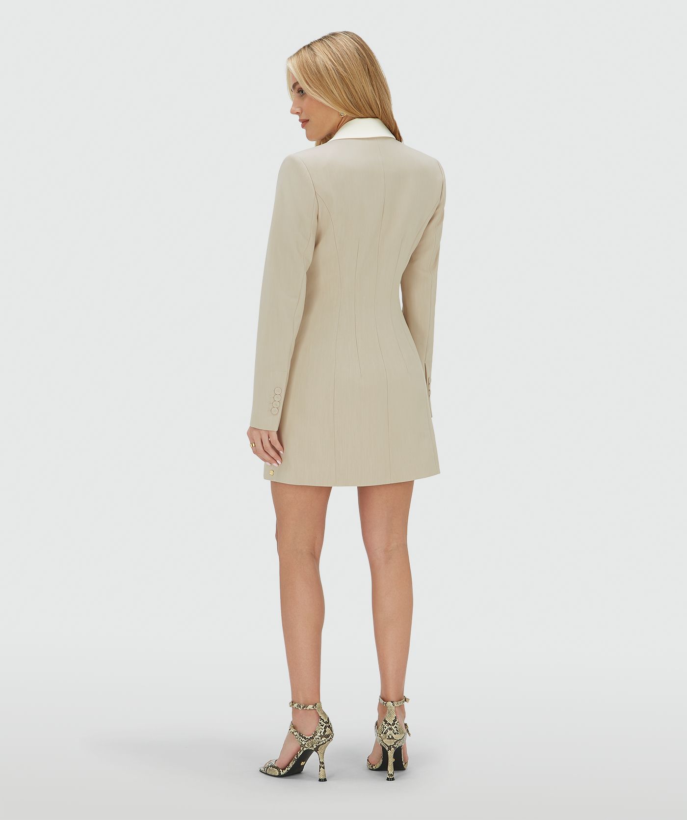 Achteraanzicht van een model in een fitted blazerjurk in de kleur Ecru Melange, waarbij de kraag en de paspelzak aan de voorzijde zijn uitgevoerd in ecru en de rest in melange