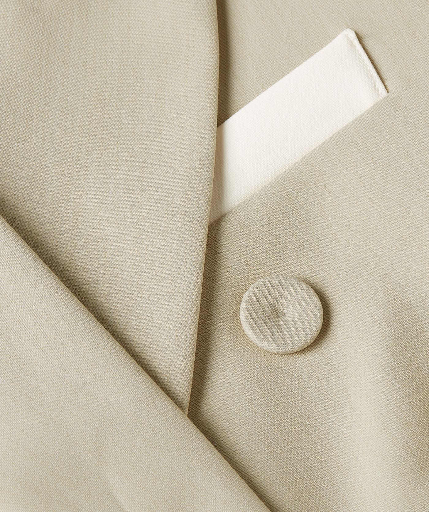 Close-up van de paspelzak in de kleur ecru, terwijl de rest van de jurk is uitgevoerd in melange