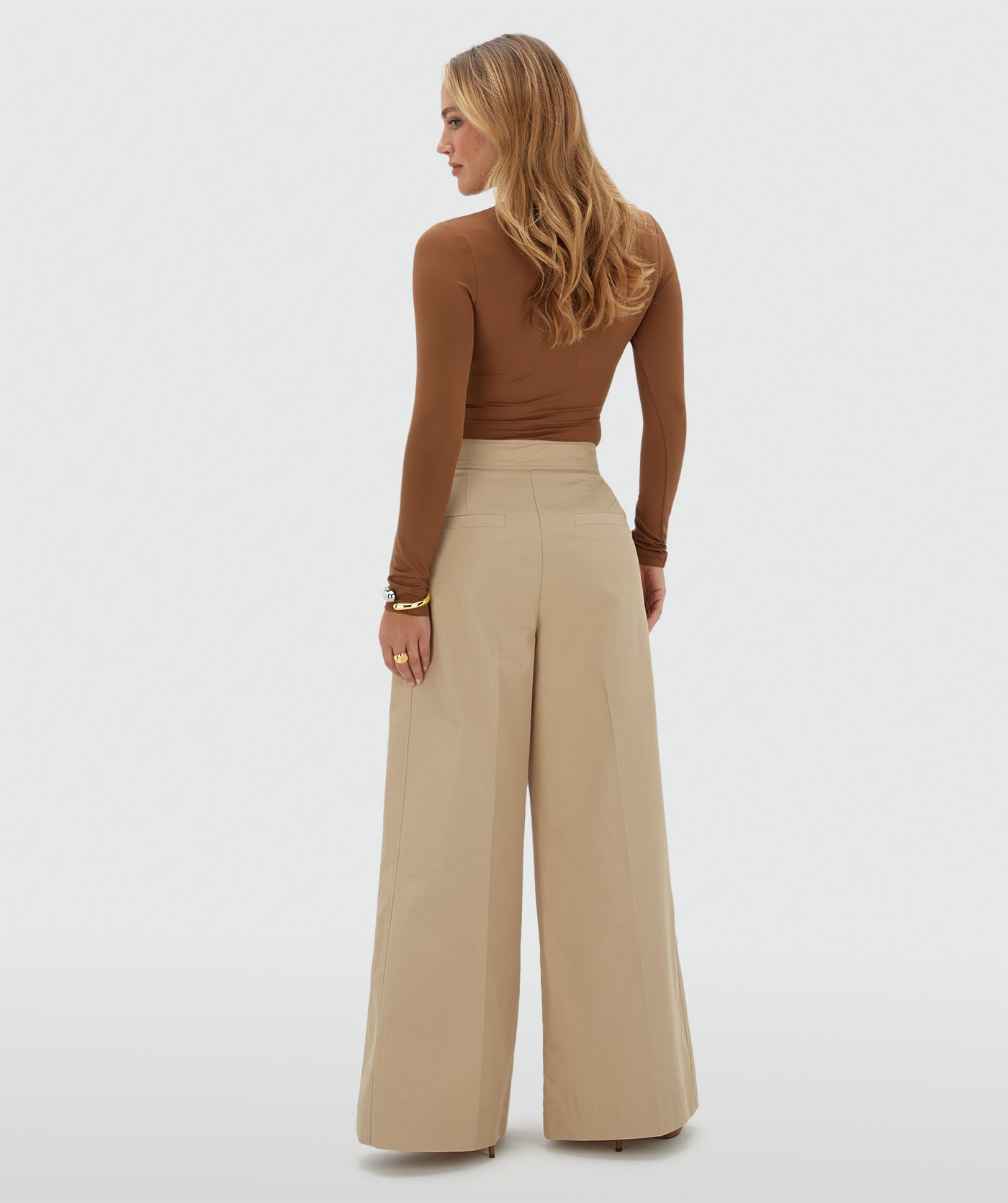 Achteraanzicht van een model in beige pantalon.