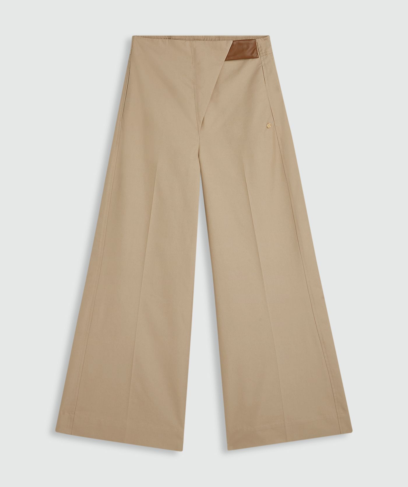 Beige pantalon met bij de sluiting een lichtbruin leren stukje zonder model, weergegeven op een lichtgrijze achtergrond.