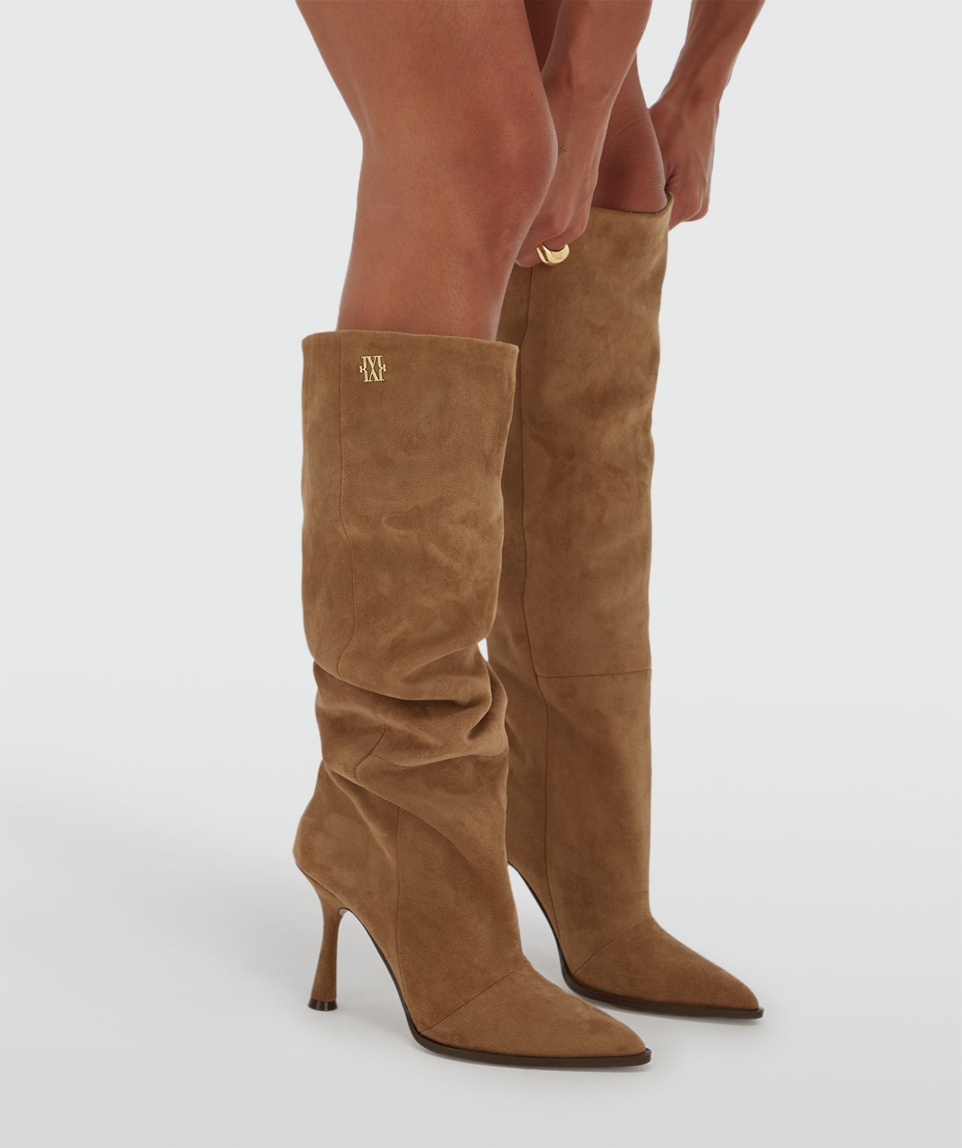 Model draagt hoge suede bruine laarzen.