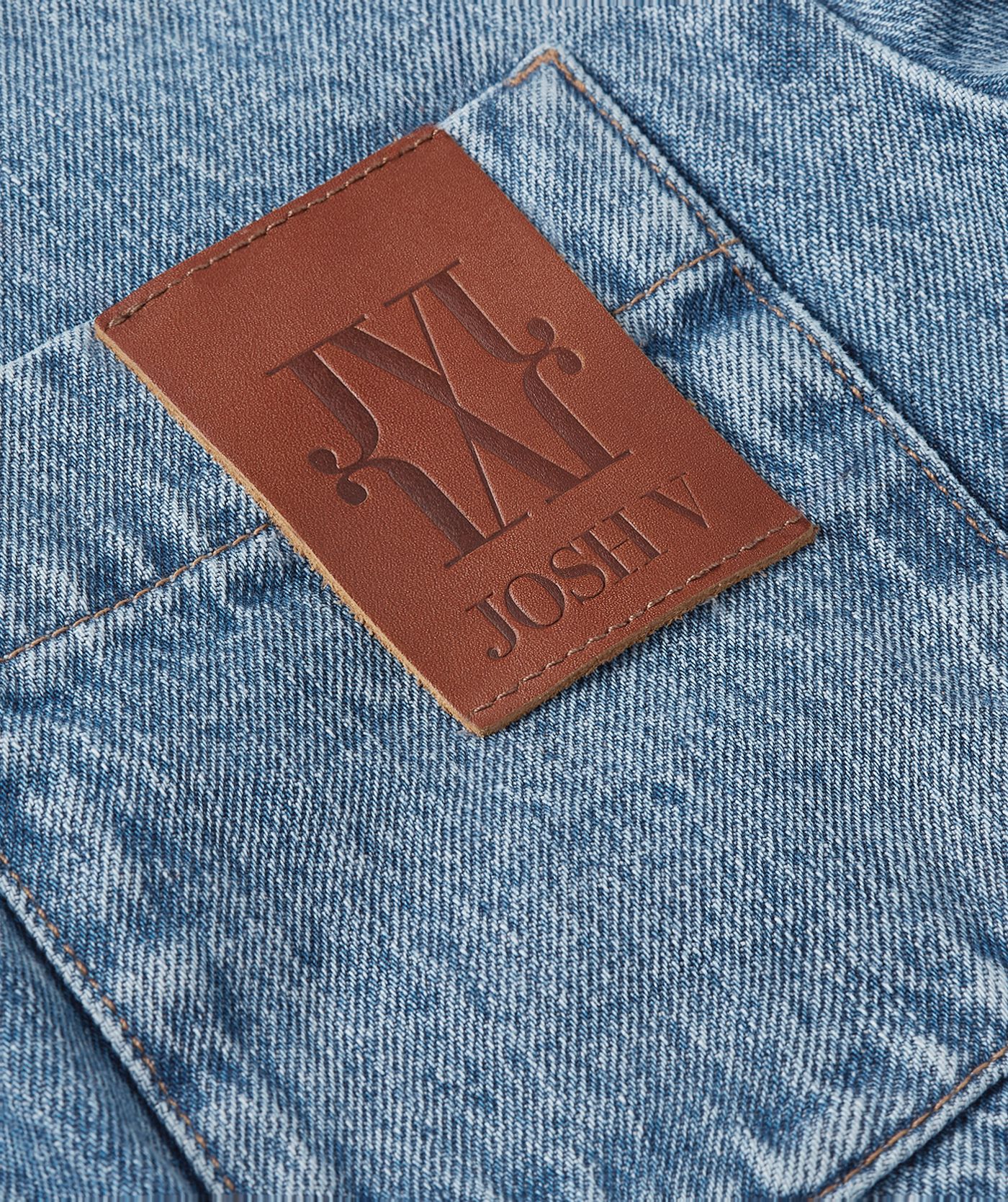 Close-up van een oversized denim blouse met JOSH V embleem