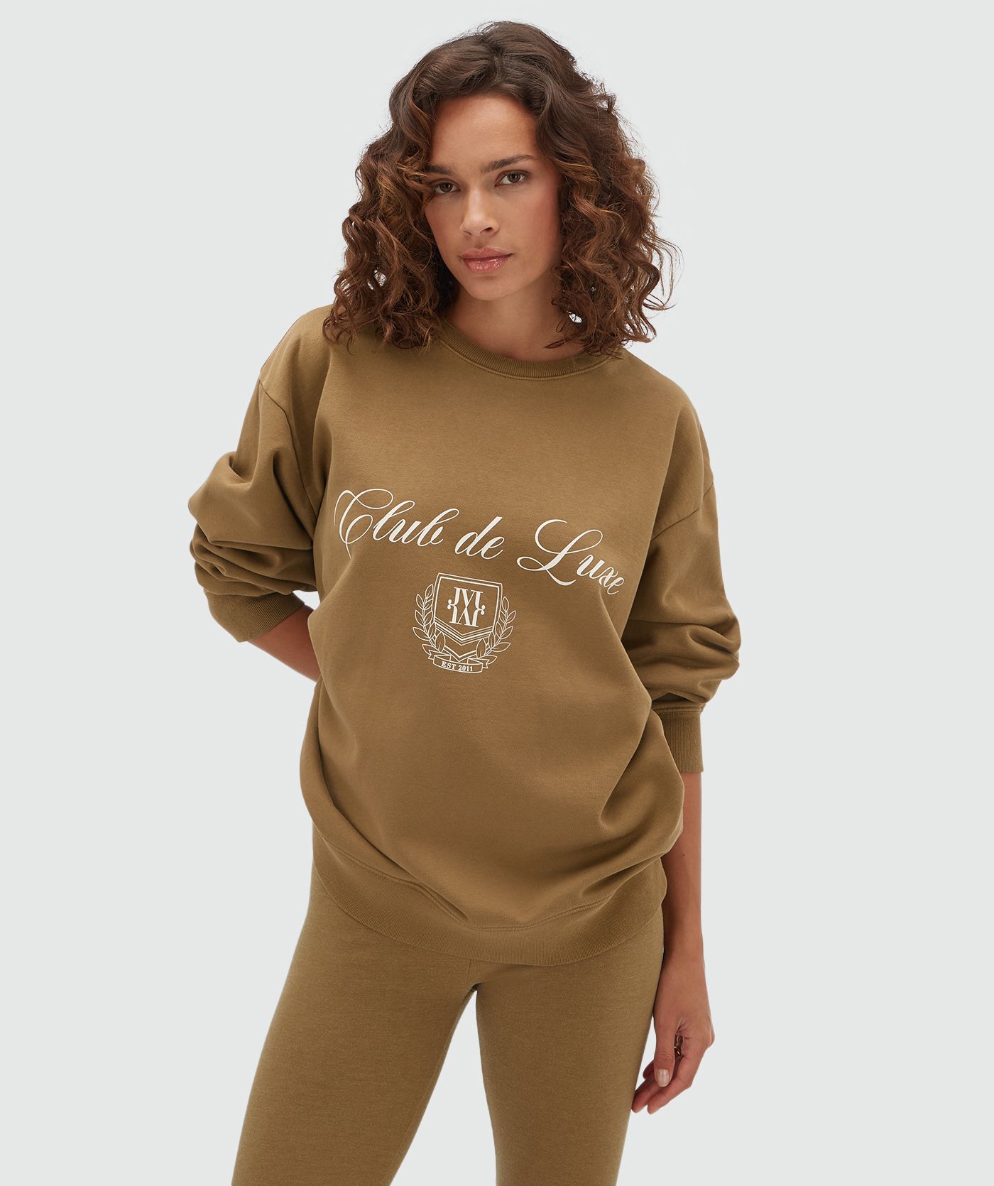 Model draagt een sweater in de kleur Khaki met tekst.