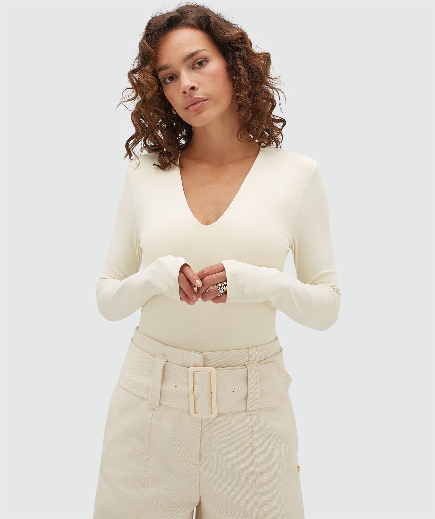 Model draagt een crème body met lange mouwen en een v-hals.