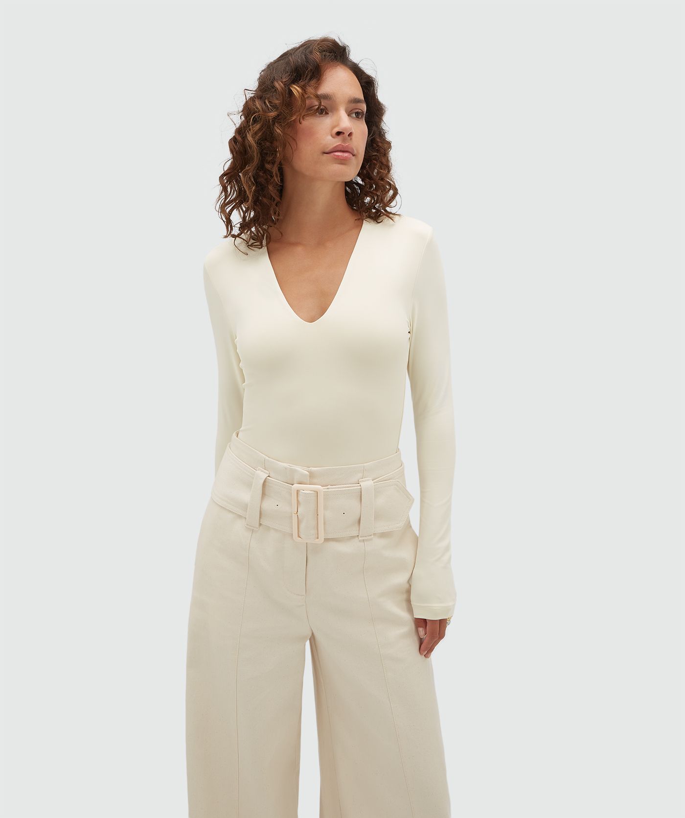 Model draagt een crème body met lange mouwen en een v-hals.