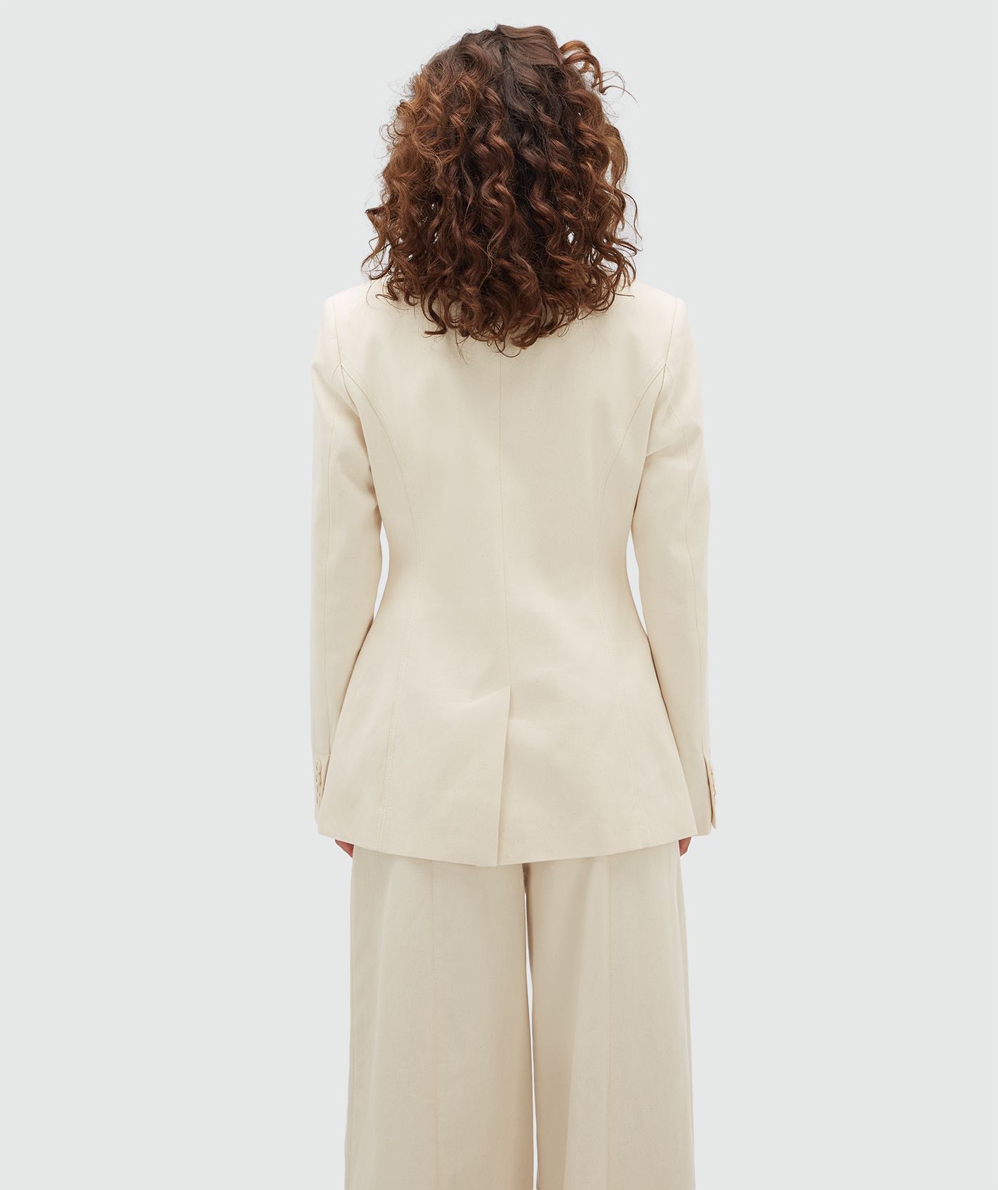 Achteraanzicht van een model in een crème blazer.