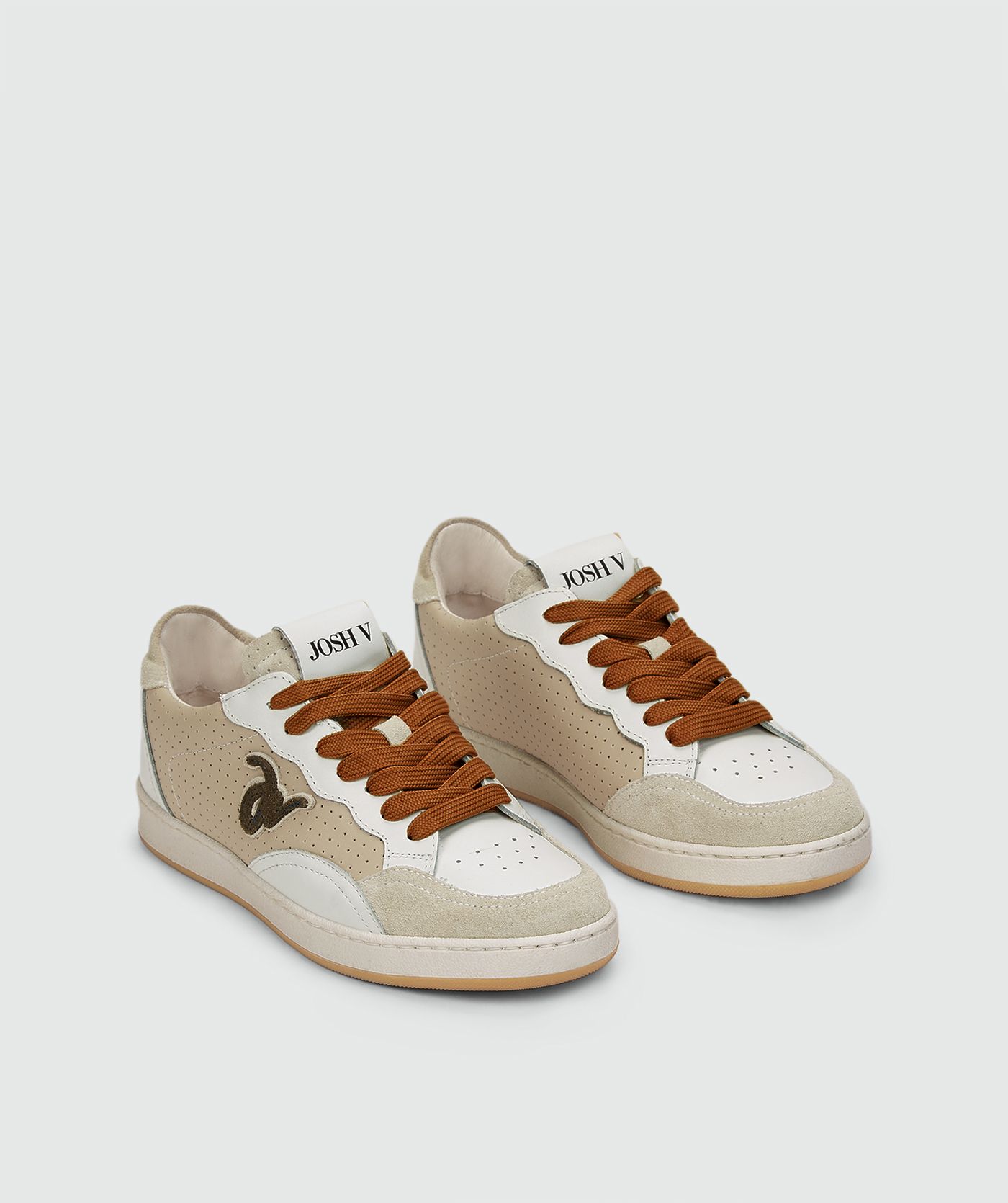 Beige sneakers met een groene touch zonder model, weergegeven op een lichtgrijze achtergrond. 
