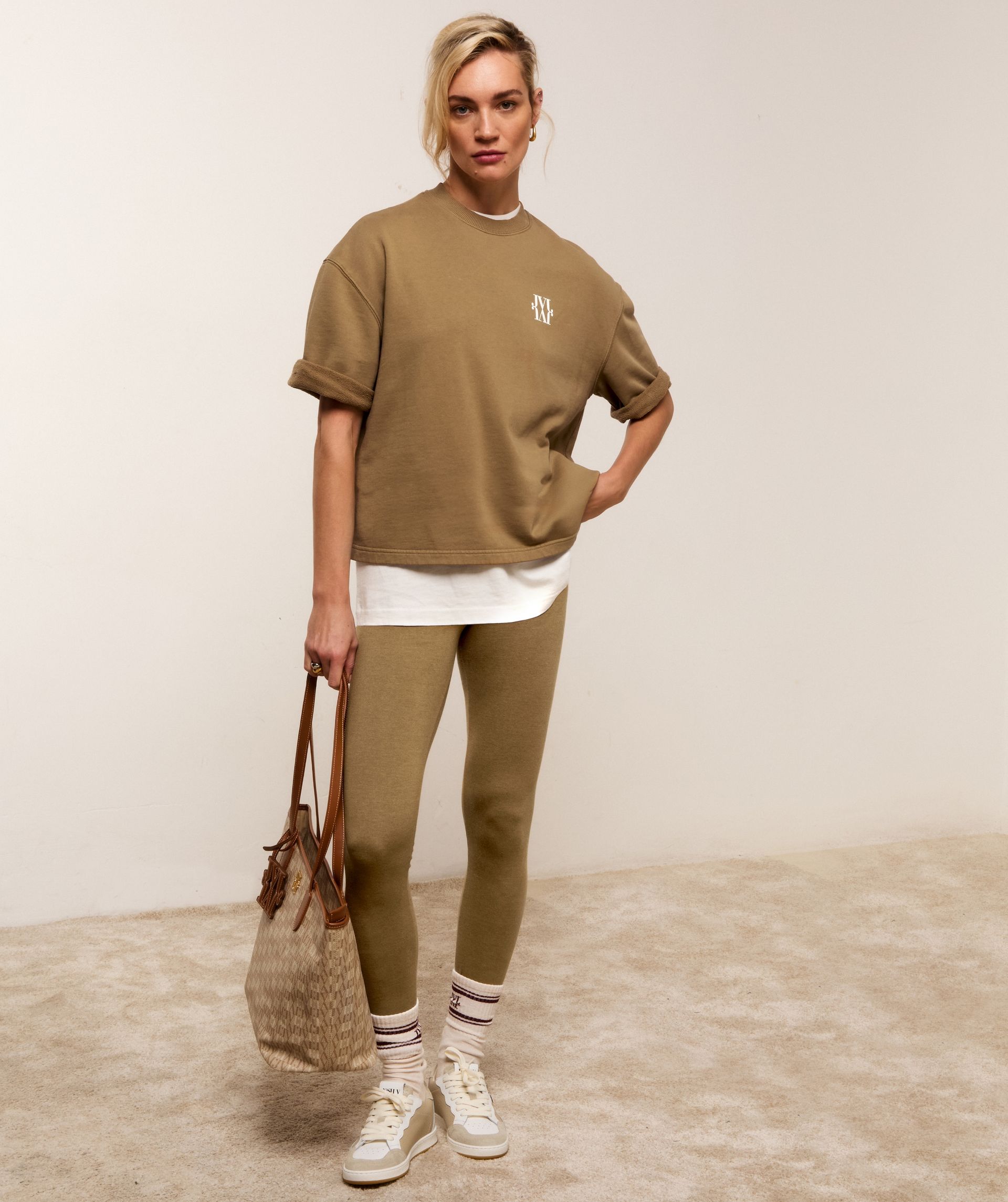 Model draagt beige sneakers met een groene touch inclusief beige veters. 