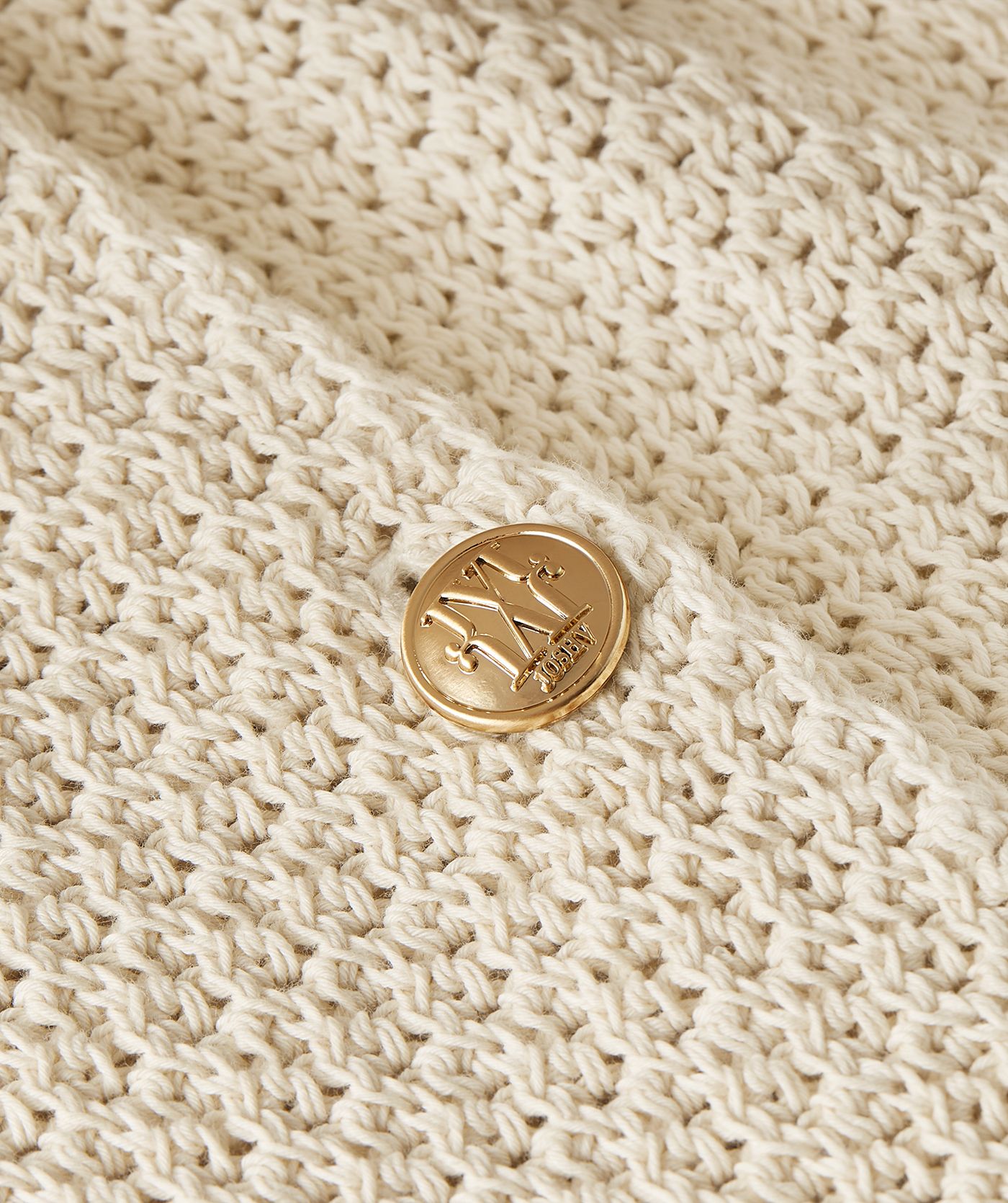 Close-up van de knoopsluiting van een ecrukleurig vest in een regular fit