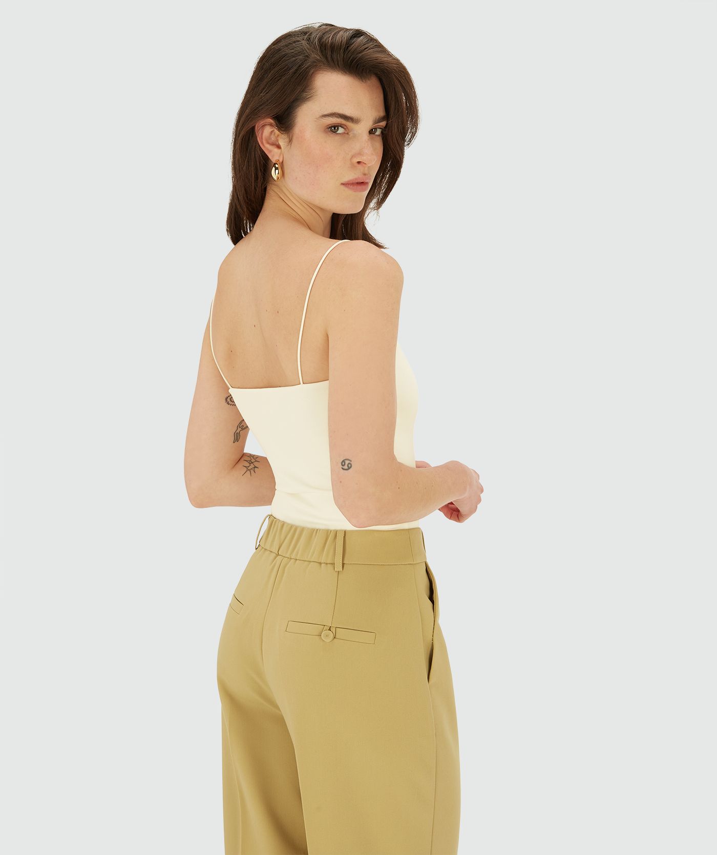 Model van opzij draagt een body met dunne bandjes in de kleur Creme White 