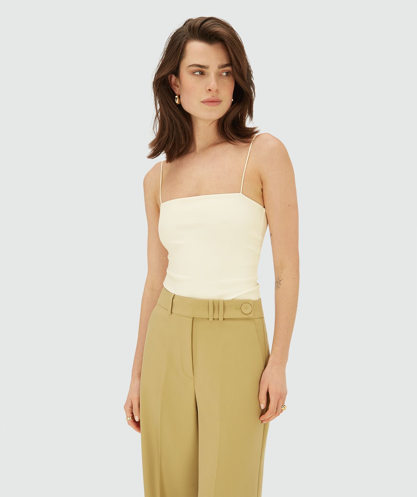 Model draagt een body met dunne bandjes in de kleur Creme White 