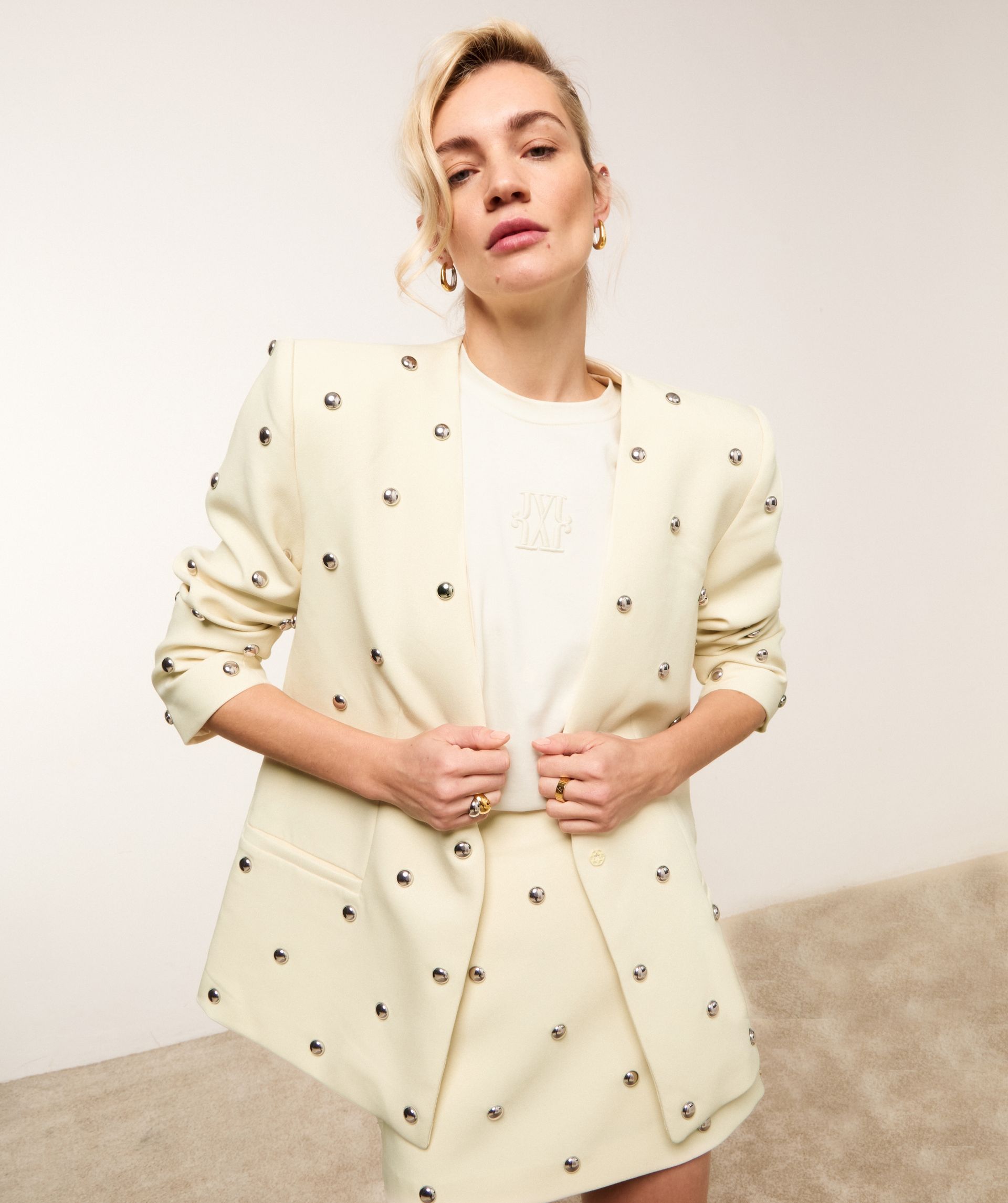 Model draagt lichtgele blazer met zilveren studs.